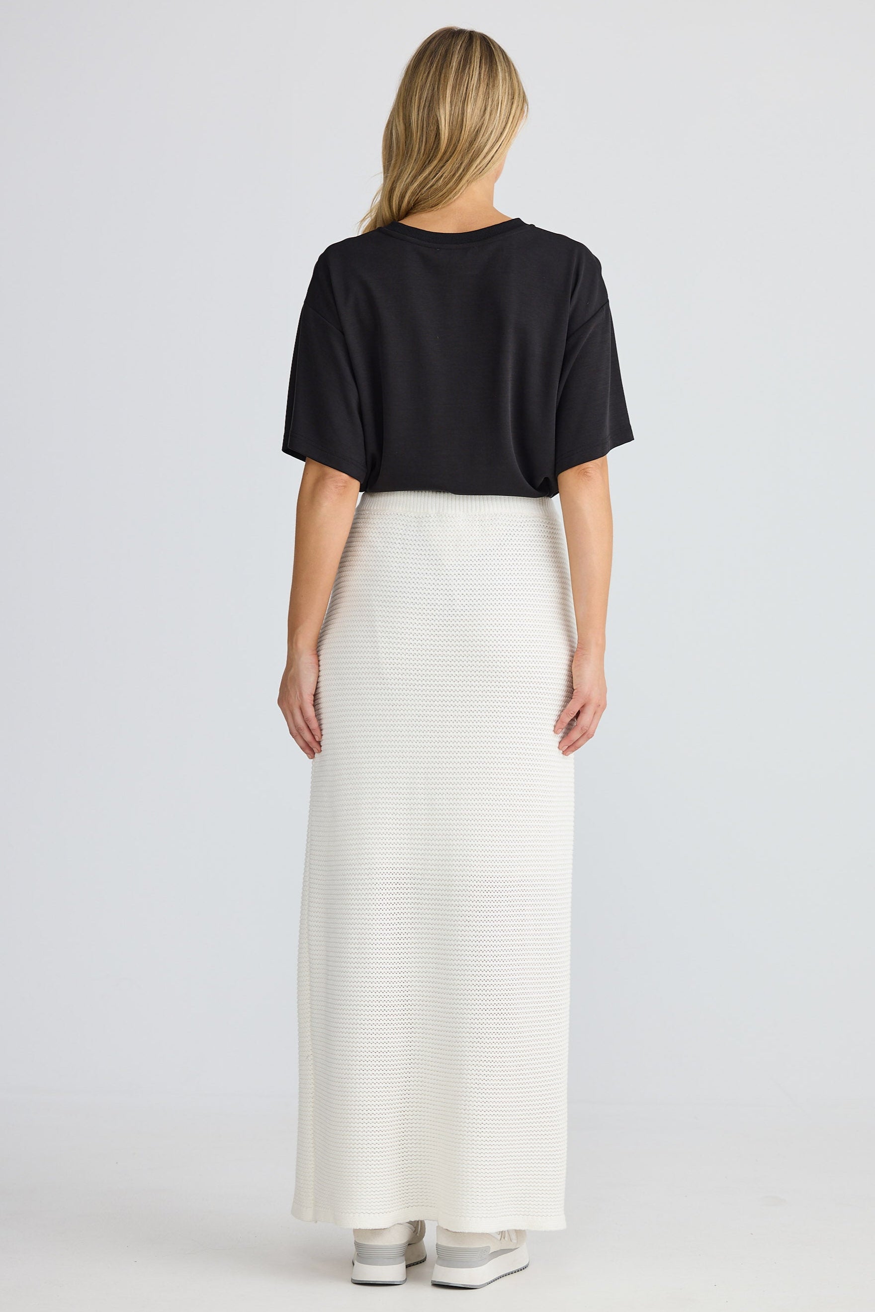 Person wearing a black top and white pants on a plain background