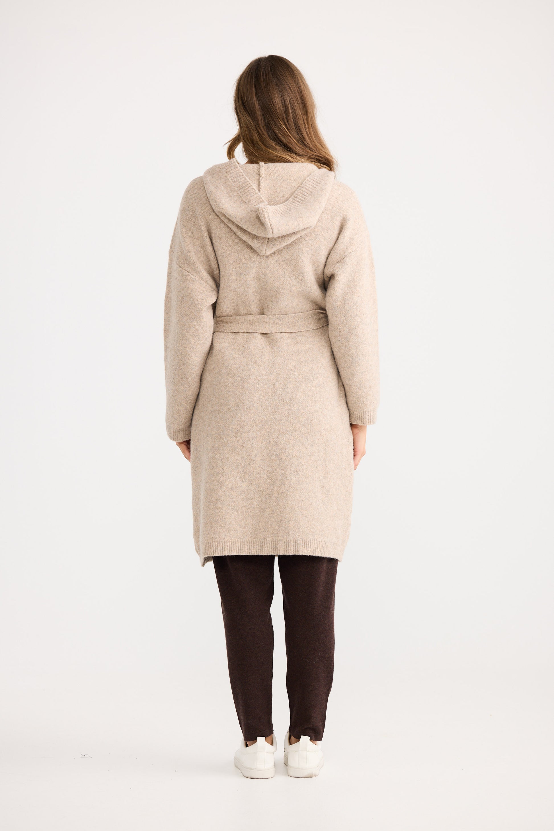 Woman wearing a beige hooded coat on a white background