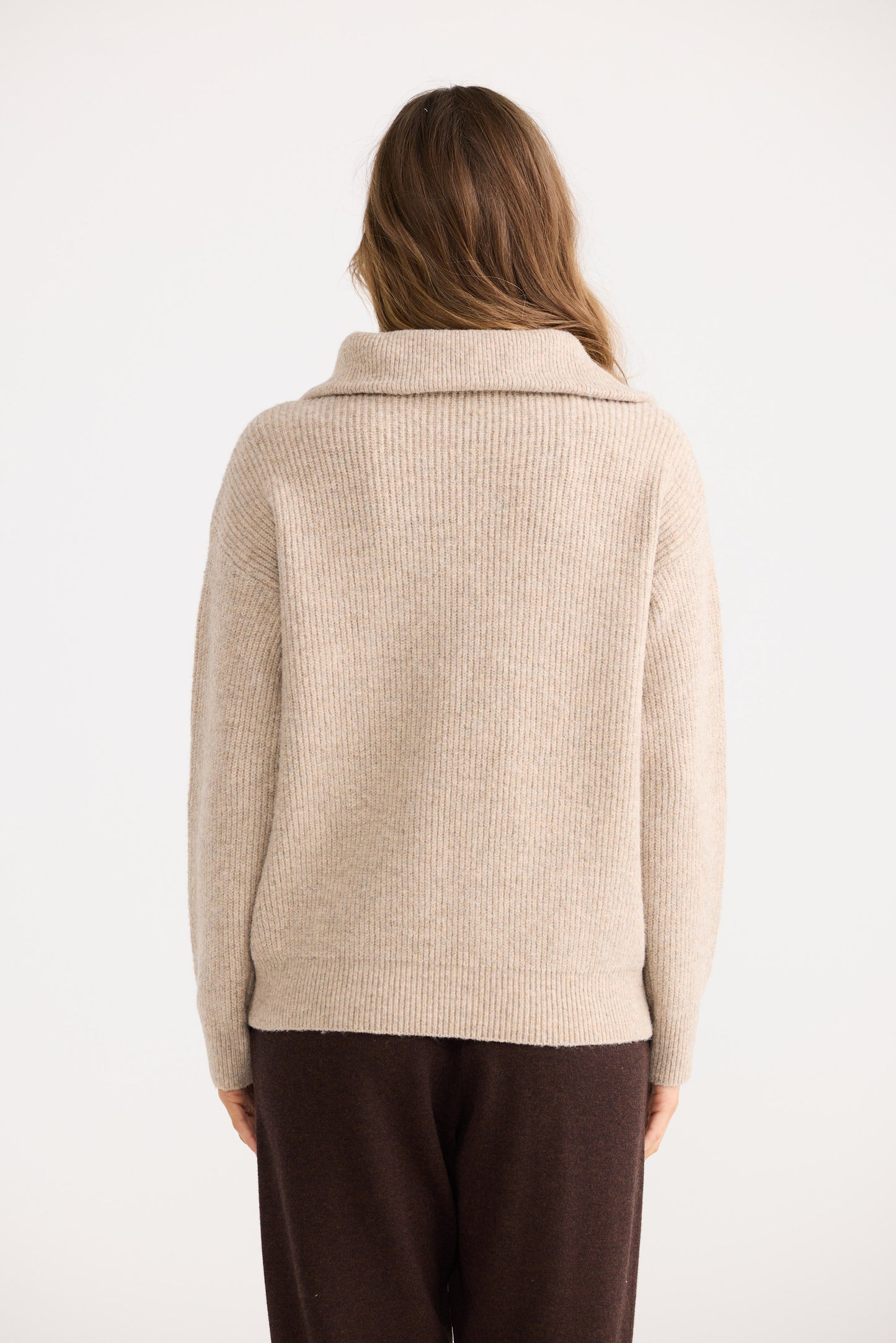 Person wearing a beige sweater with a white background