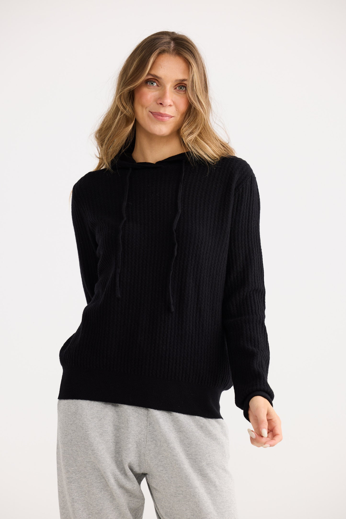 Woman wearing a black sweater and gray pants on a white background