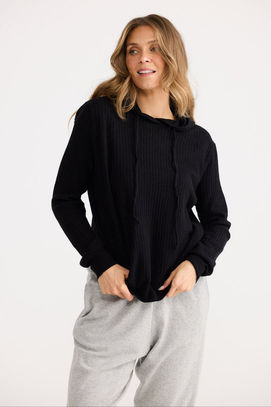 Woman wearing a black sweater and gray pants on a white background
