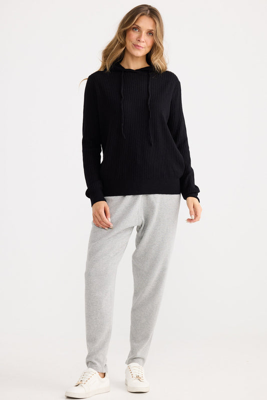 Woman wearing a black sweater and gray pants on a white background