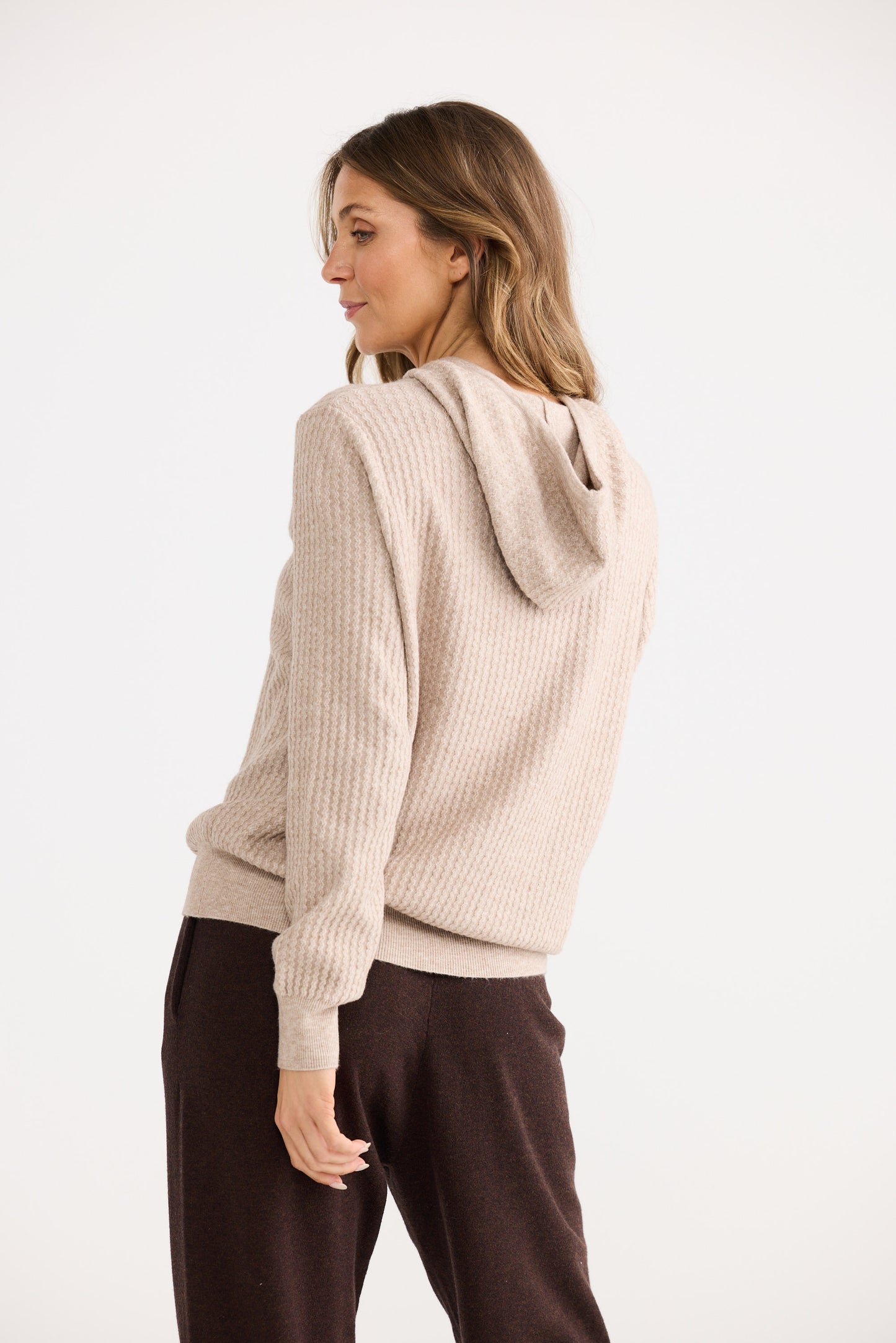 Woman wearing a beige hooded sweater on a white background