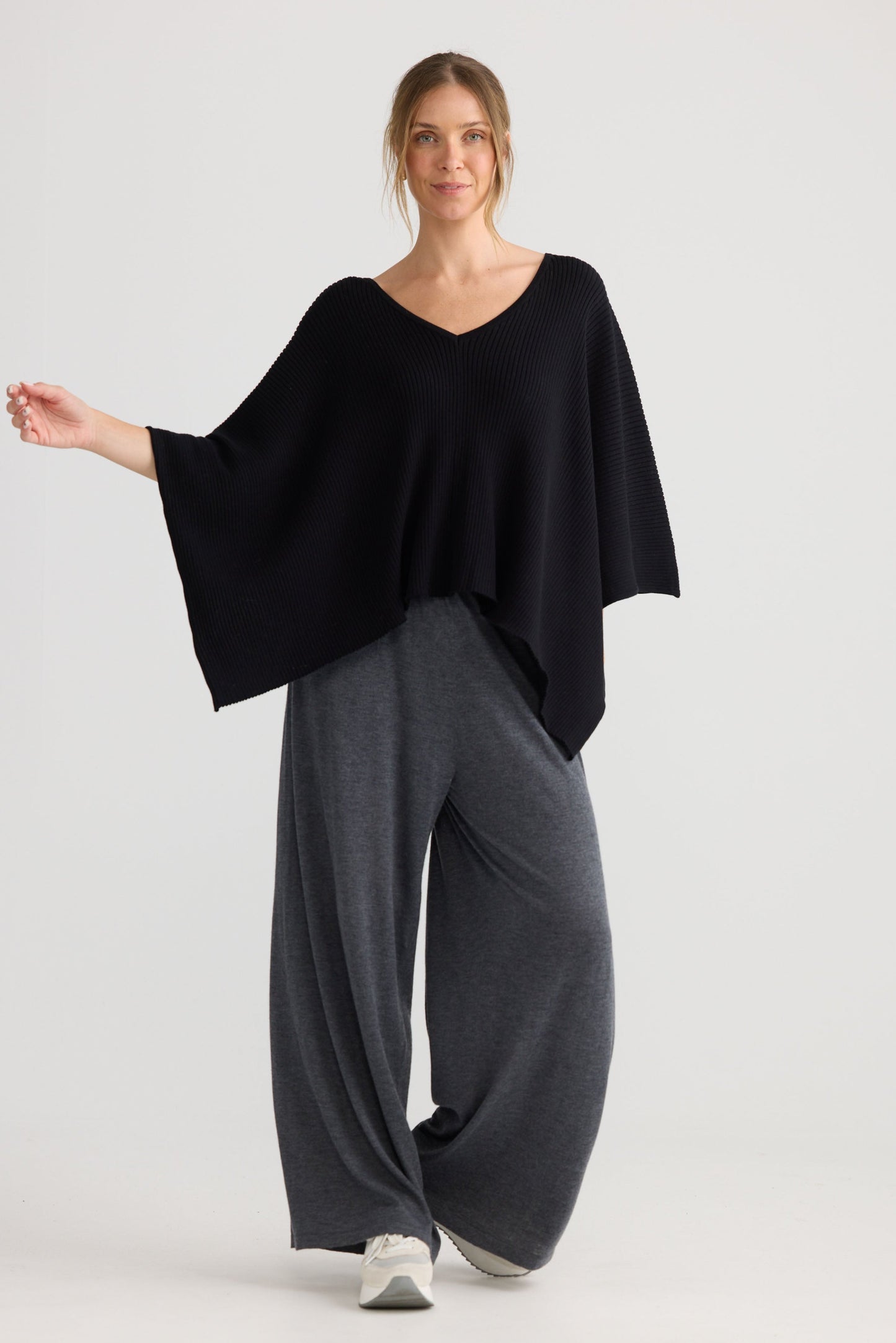 Model wearing Affirm Cape in black, showing draped cape shape.