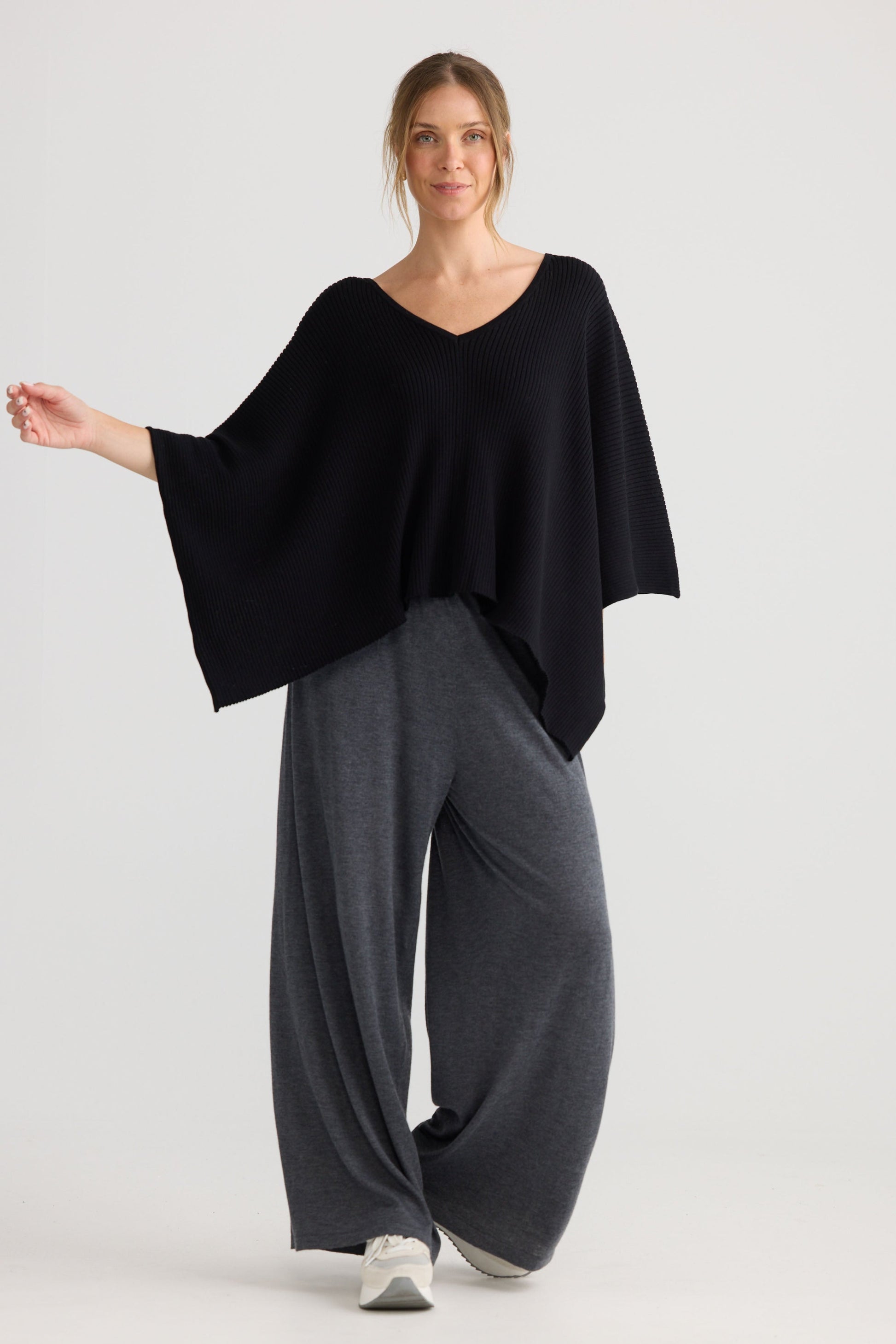 Model wearing Affirm Cape in black, showing draped cape shape.