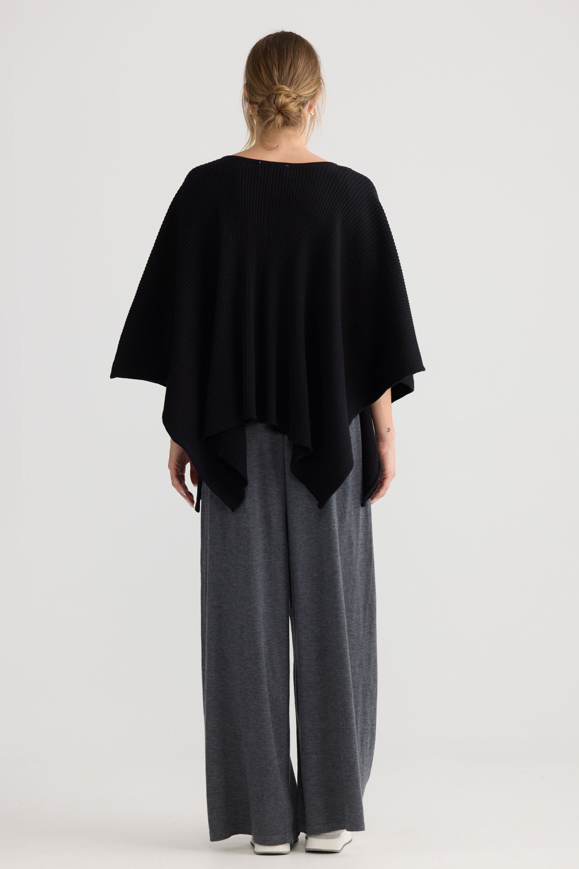Model wearing Affirm Cape in black, styled for everyday wear.