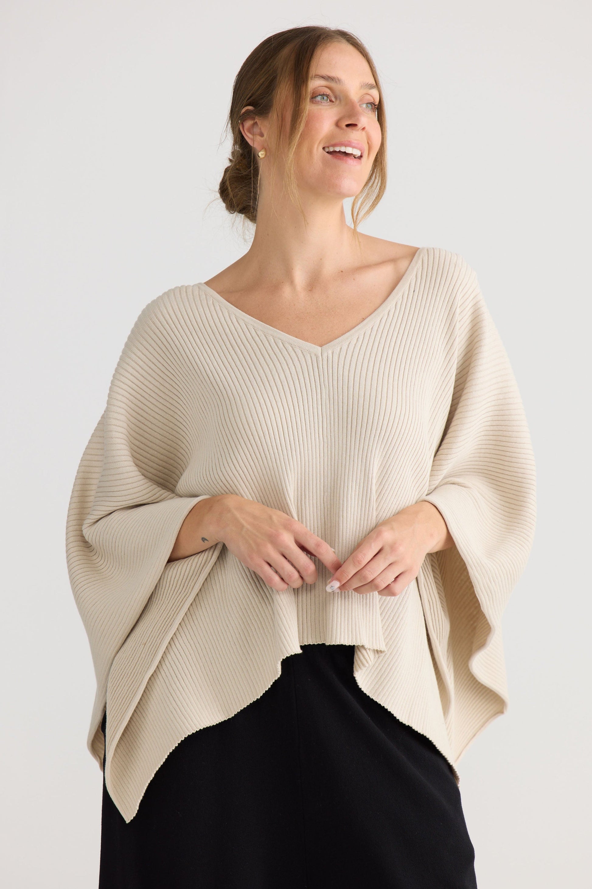 Model wearing Affirm Cape in cream, showing draped cape shape.