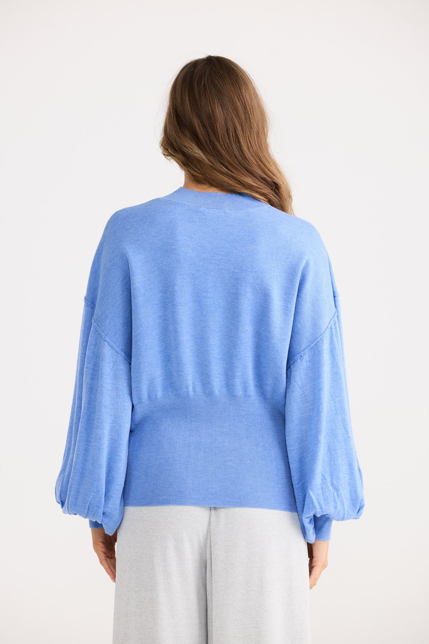 Woman wearing a light blue sweater with a plain white background