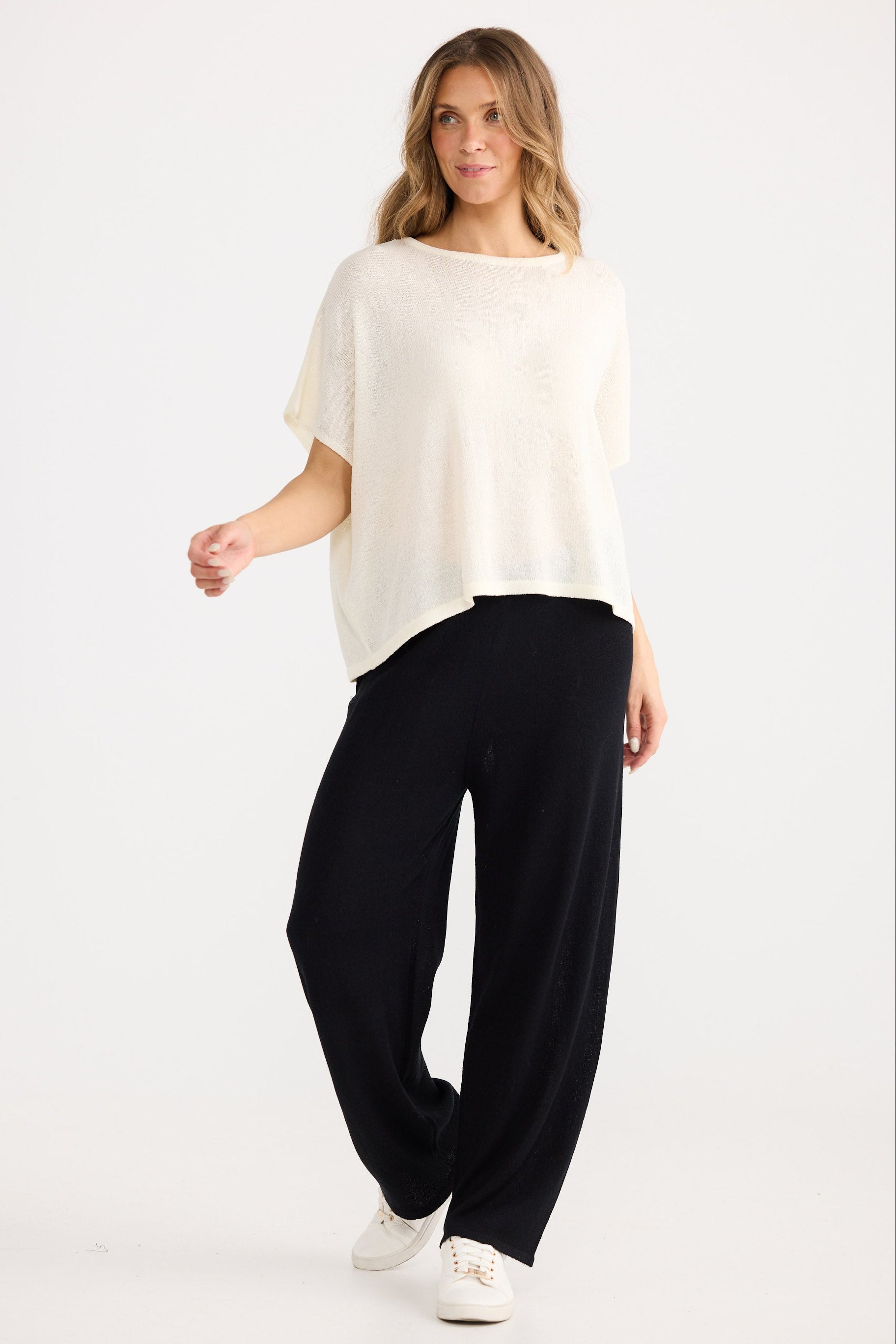 Woman wearing a white top and black pants on a white background