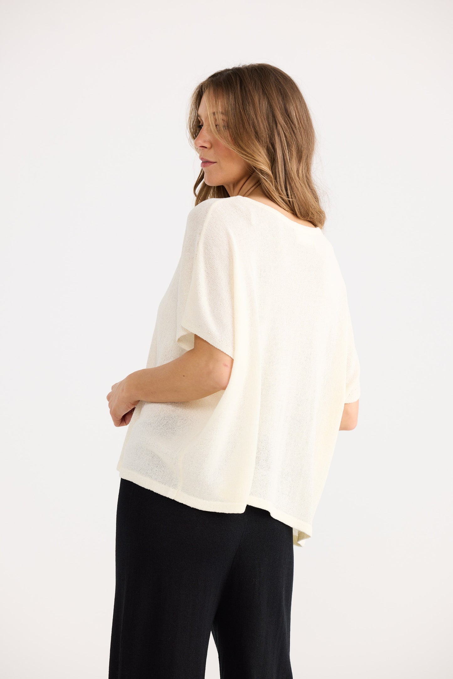 Woman wearing a white blouse and black pants on a white background