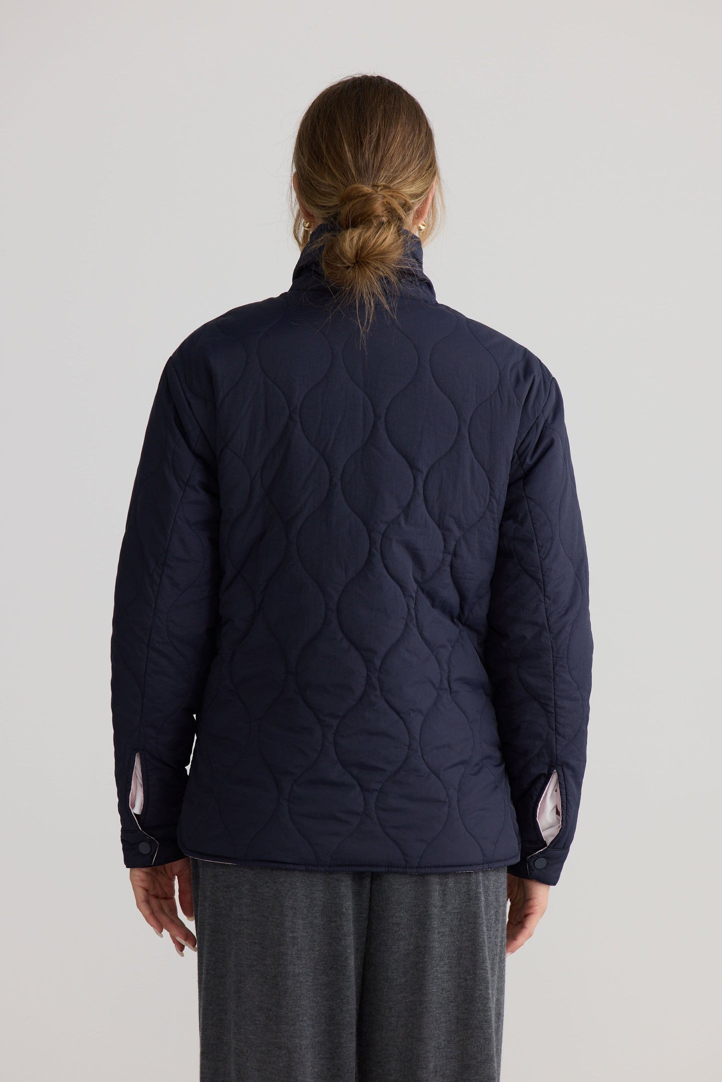 Model wearing Ellis Puffer in navy with pink, studio product image.