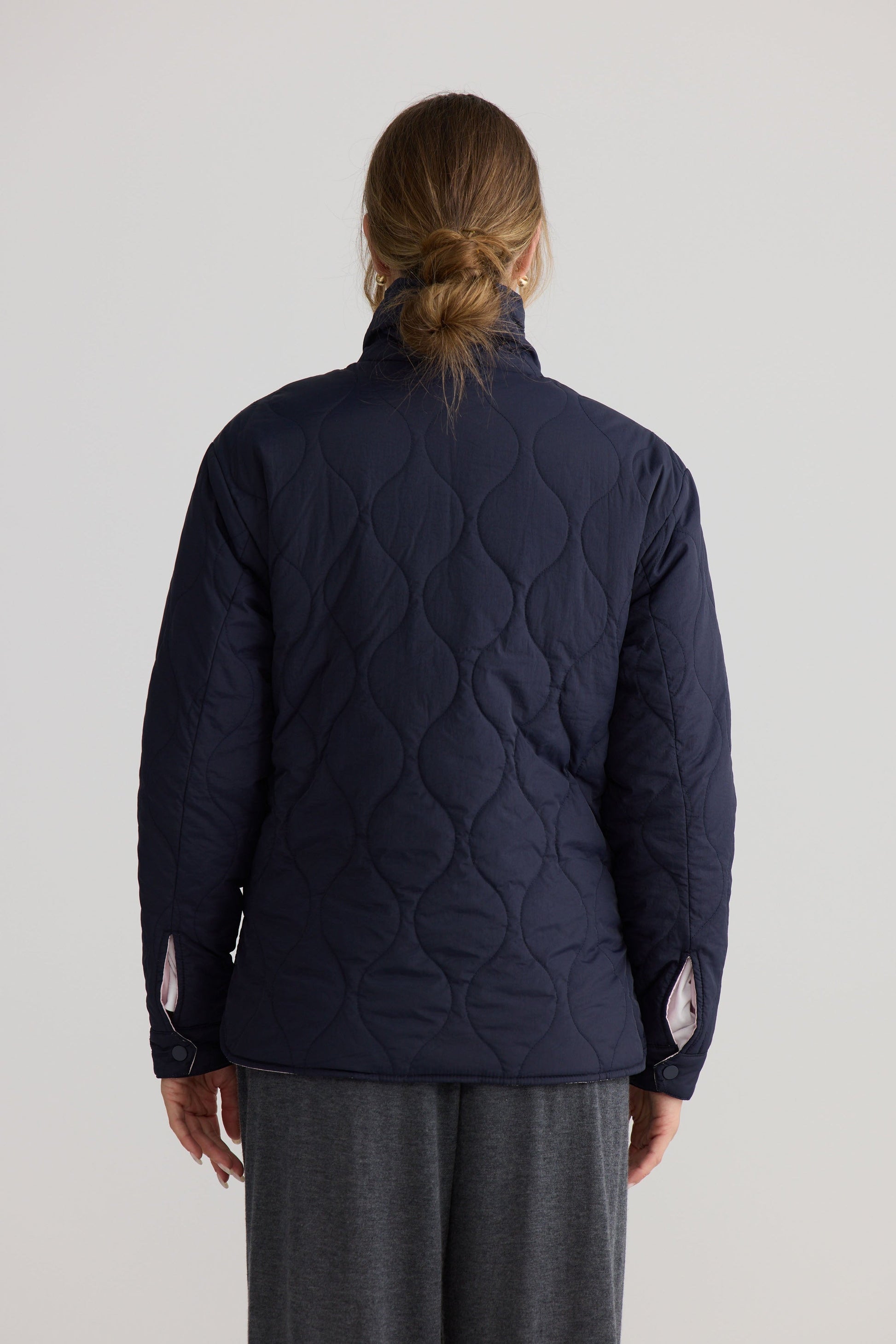 Model wearing Ellis Puffer in navy with pink, studio product image.