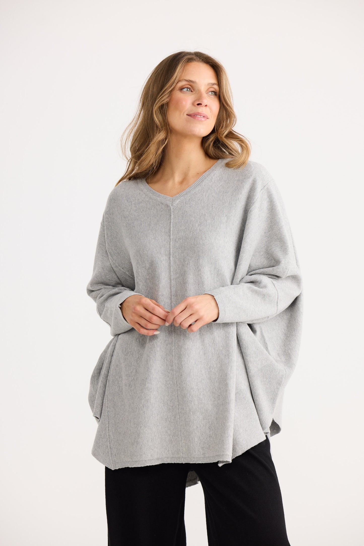 Woman wearing a gray poncho on a white background
