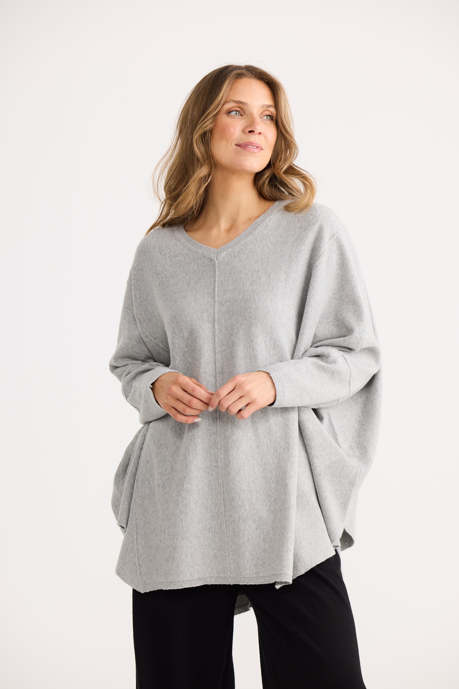 Woman wearing a gray poncho on a white background