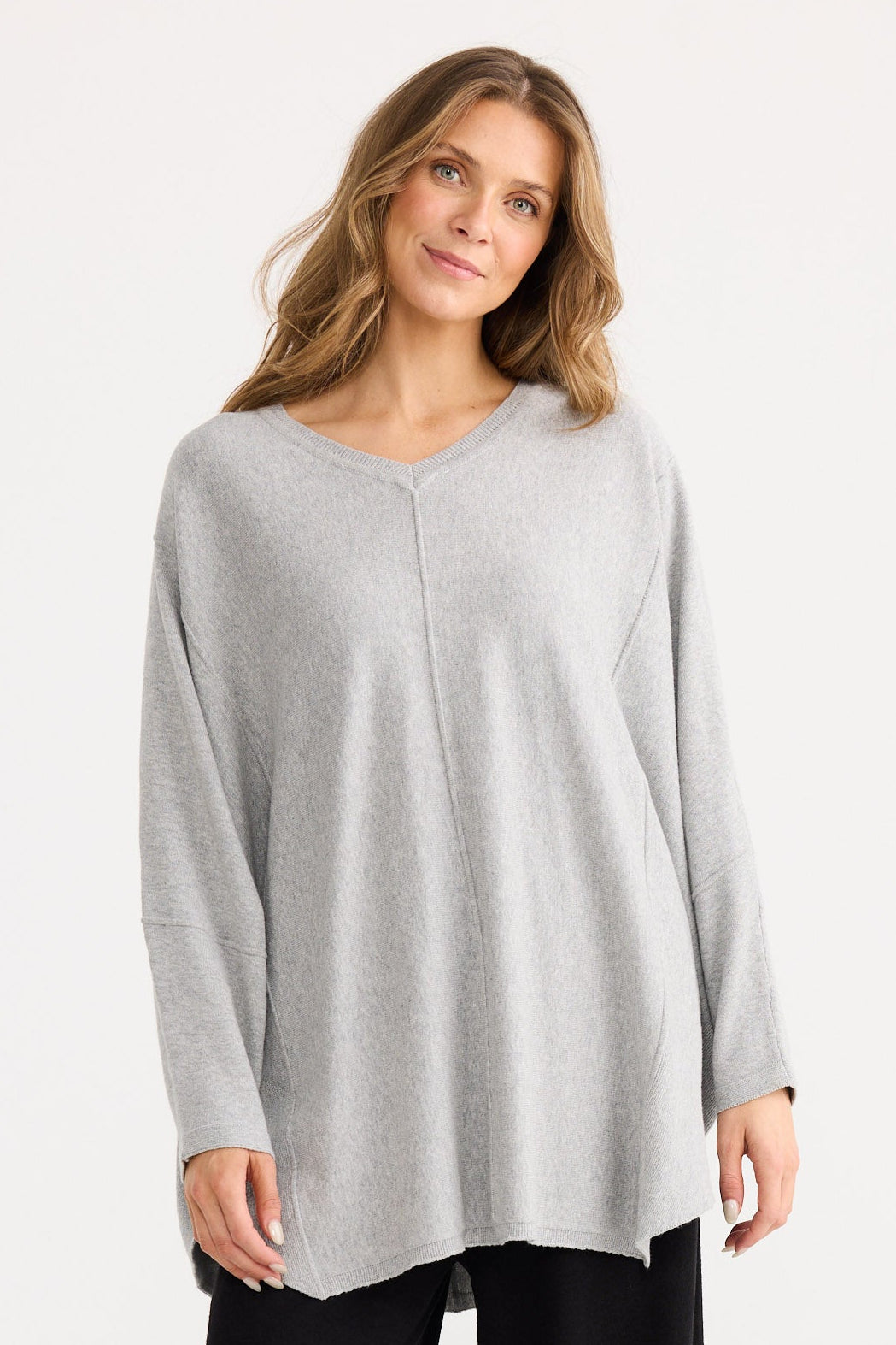 Woman wearing a light gray long-sleeve top and black wide-leg pants on a white background