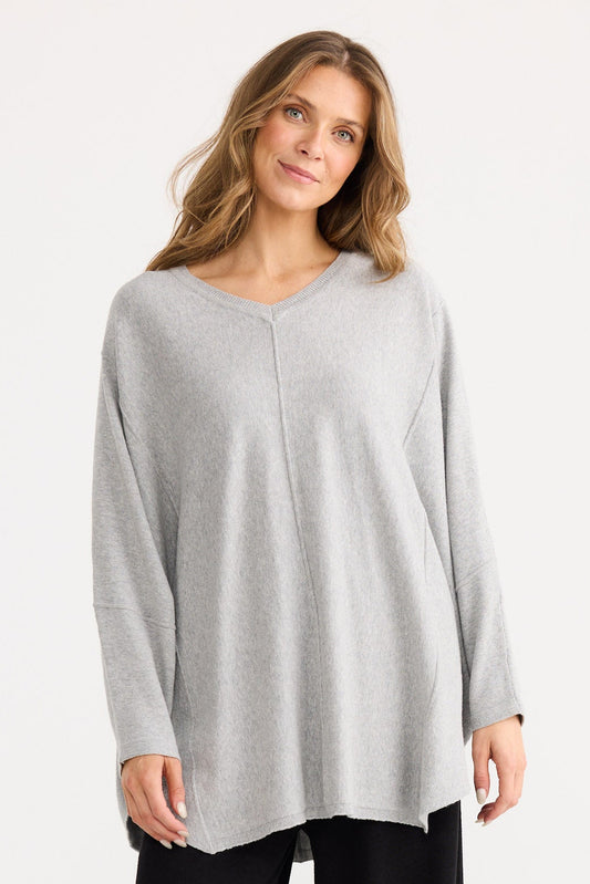 Woman wearing a light gray long-sleeve top and black wide-leg pants on a white background