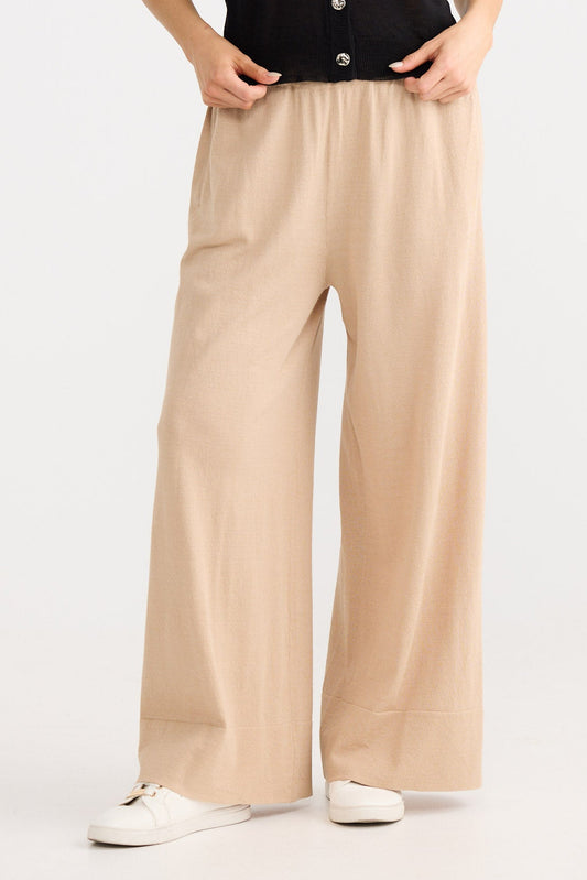 Woman wearing a black sleeveless top and beige pants on a white background