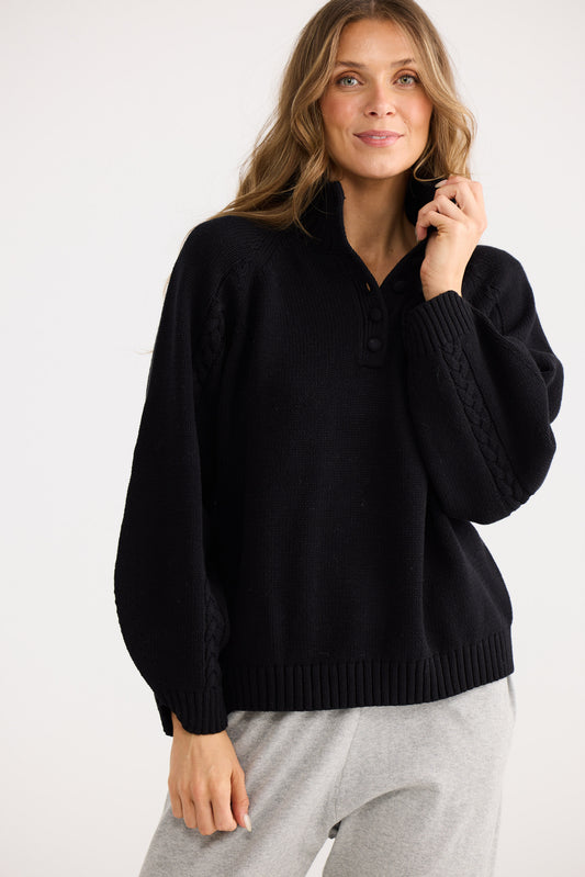 Woman wearing a black sweater and gray pants on a white background