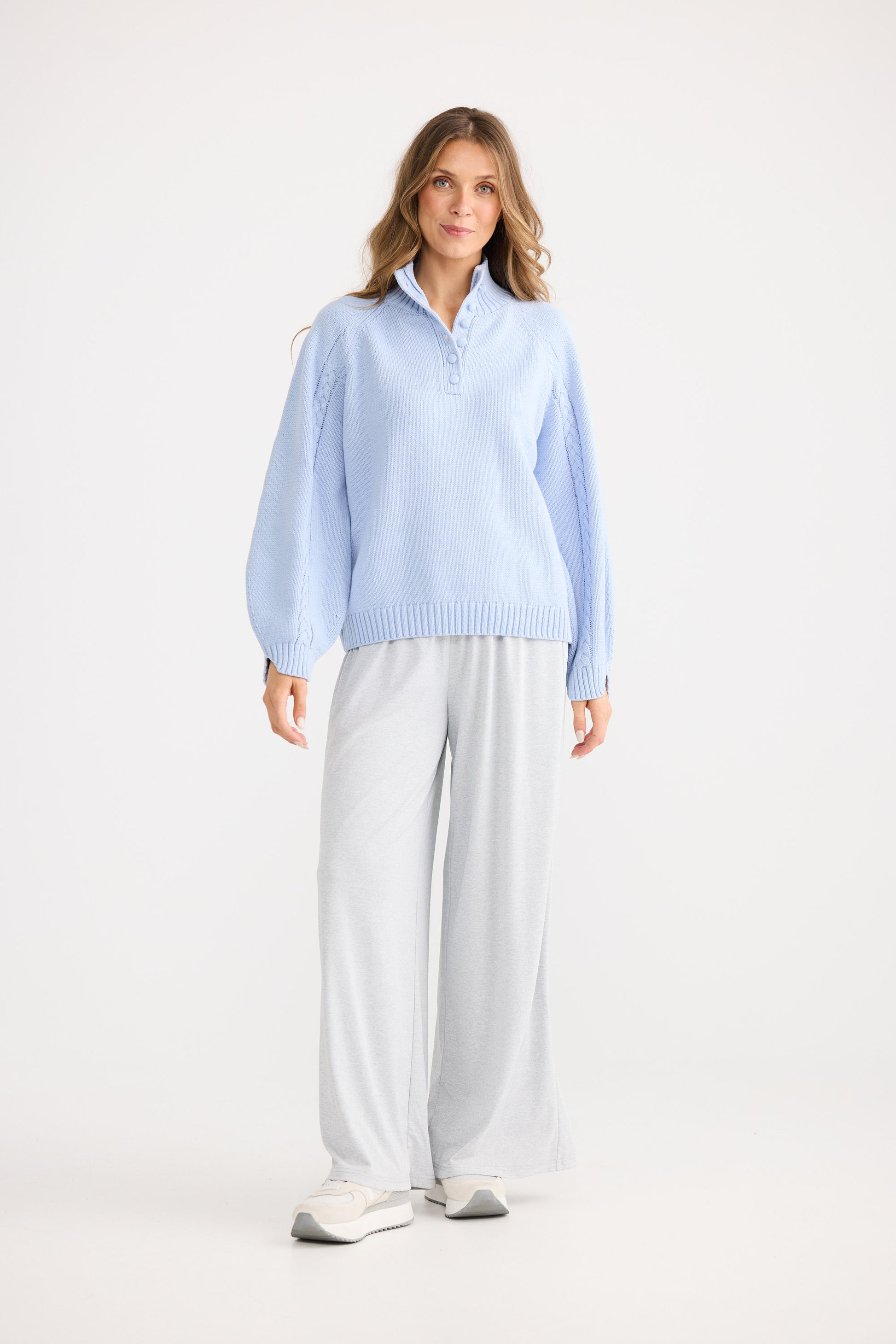 Woman wearing a light blue shirt and white pants on a white background