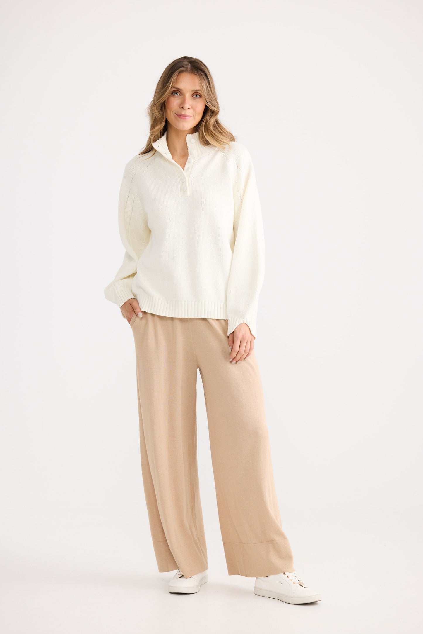 Woman wearing a white blouse and beige pants on a white background