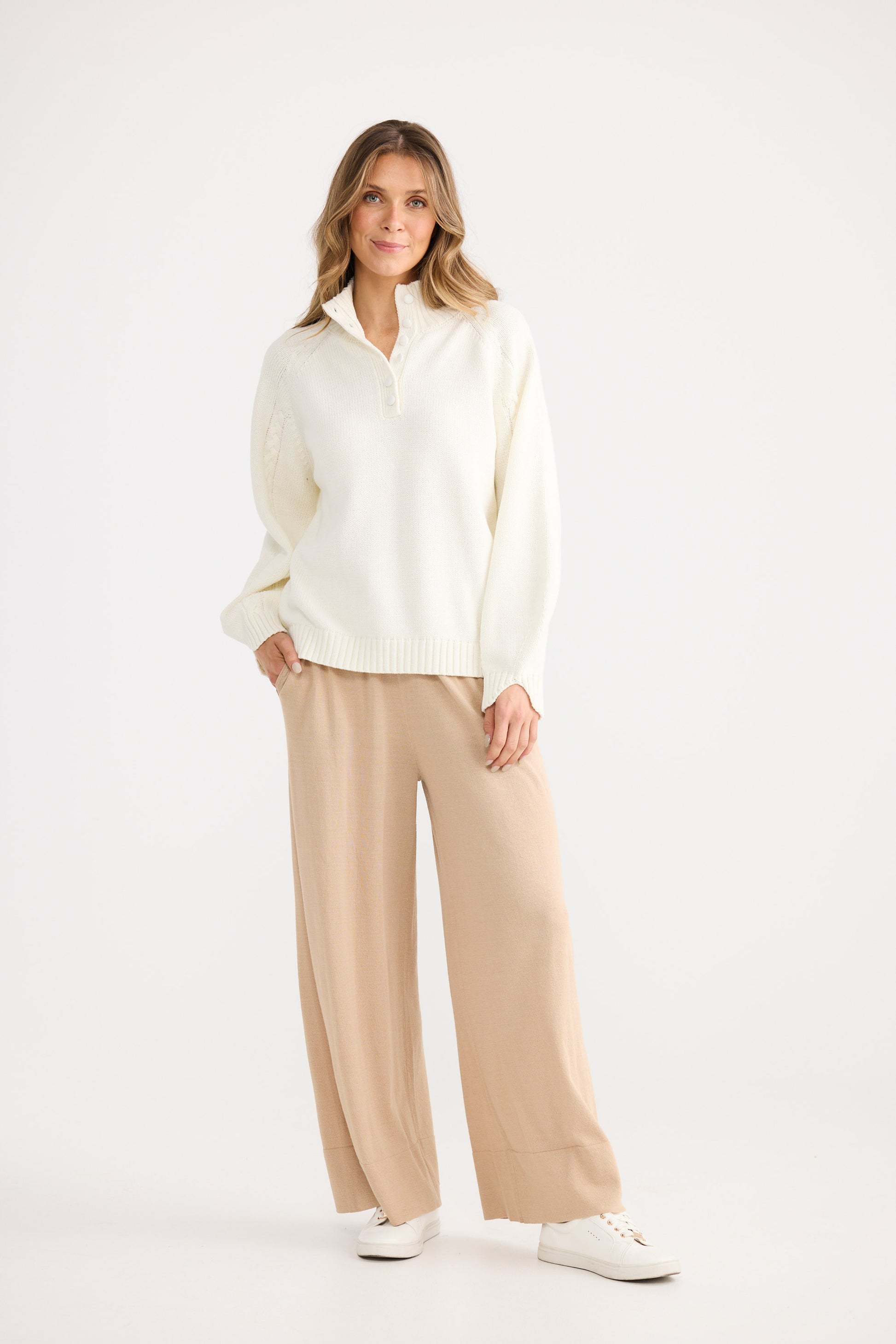 Woman wearing a white blouse and beige pants on a white background