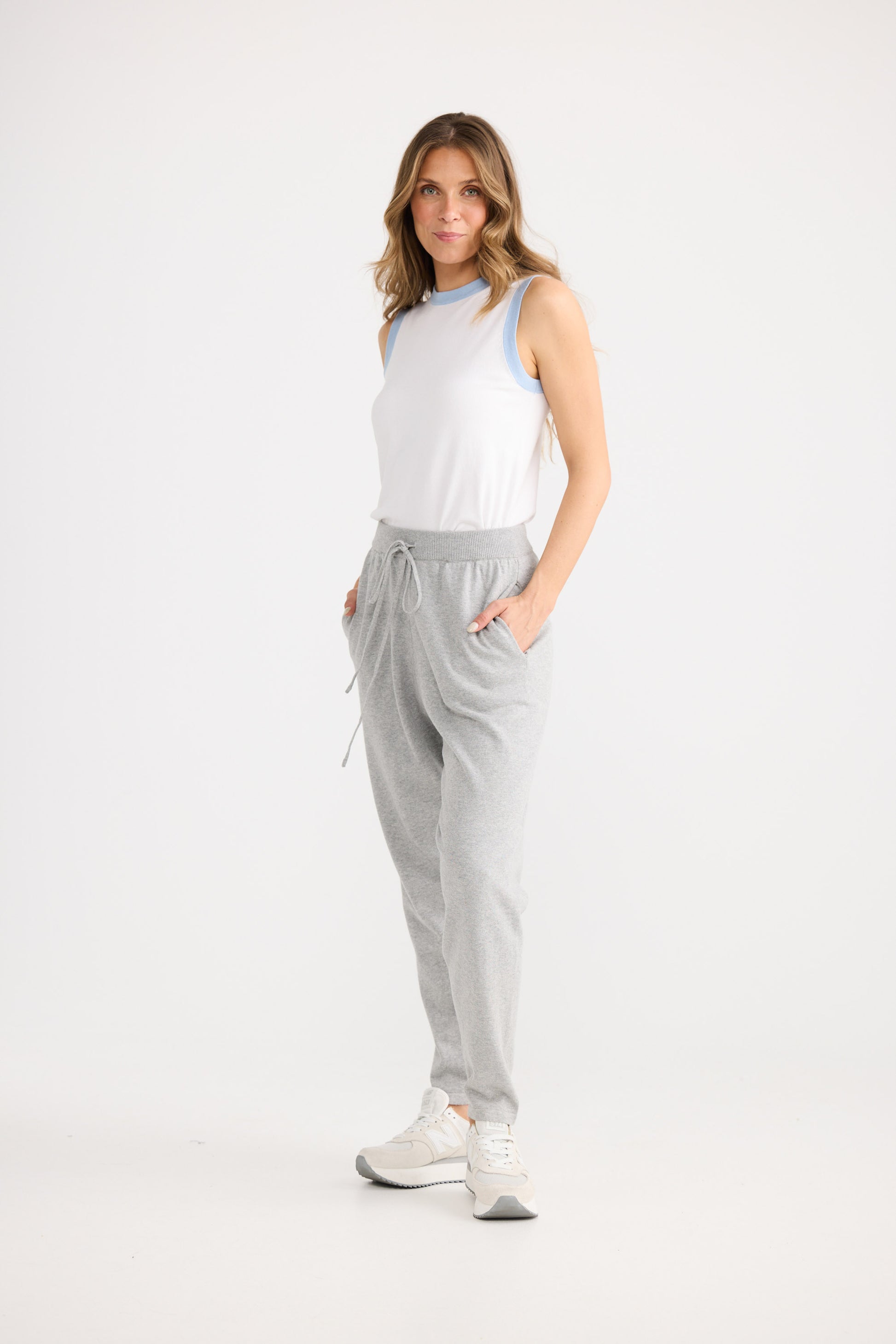 Person wearing grey pants and a white top on a white background
