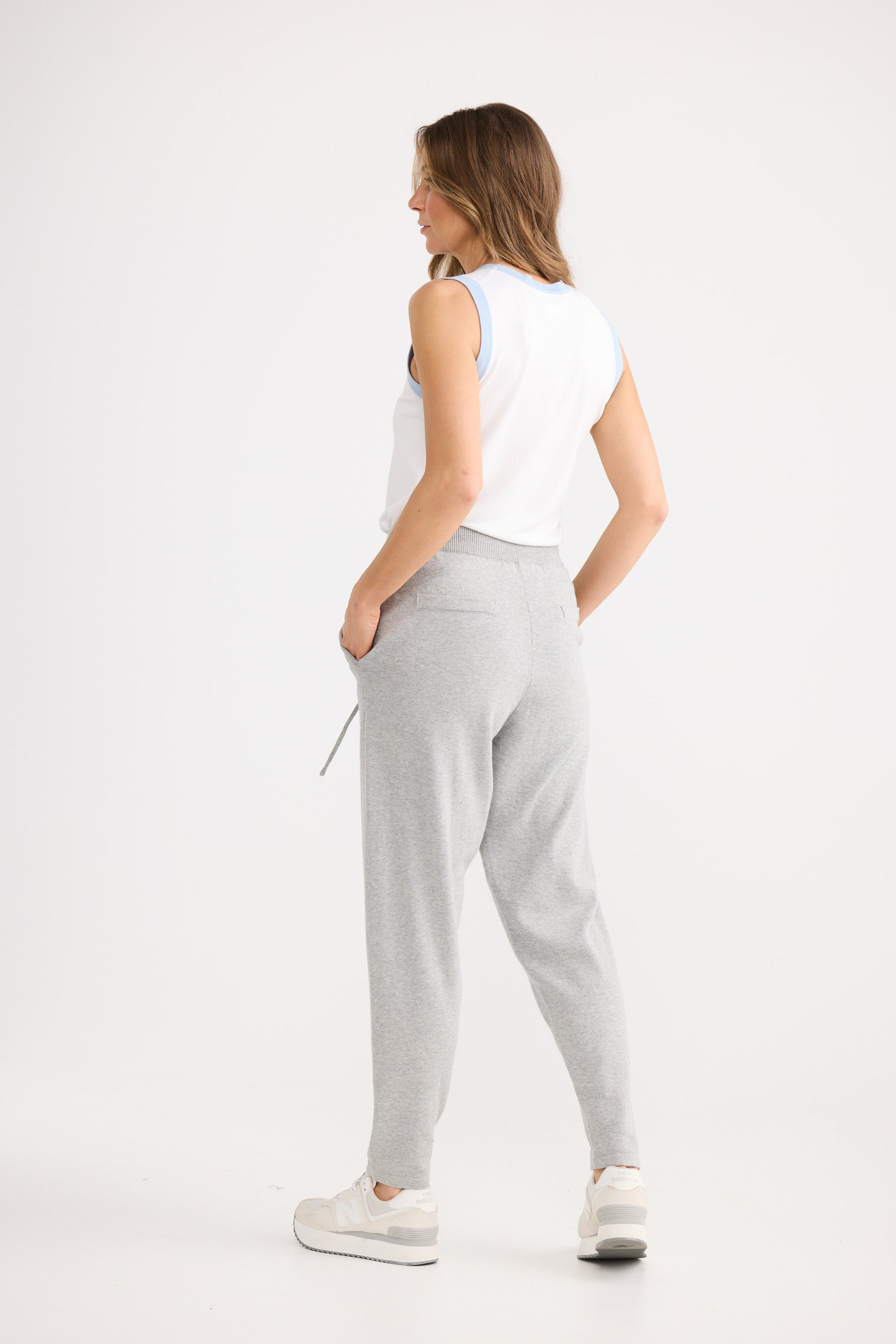 Person wearing grey pants and a white top on a white background