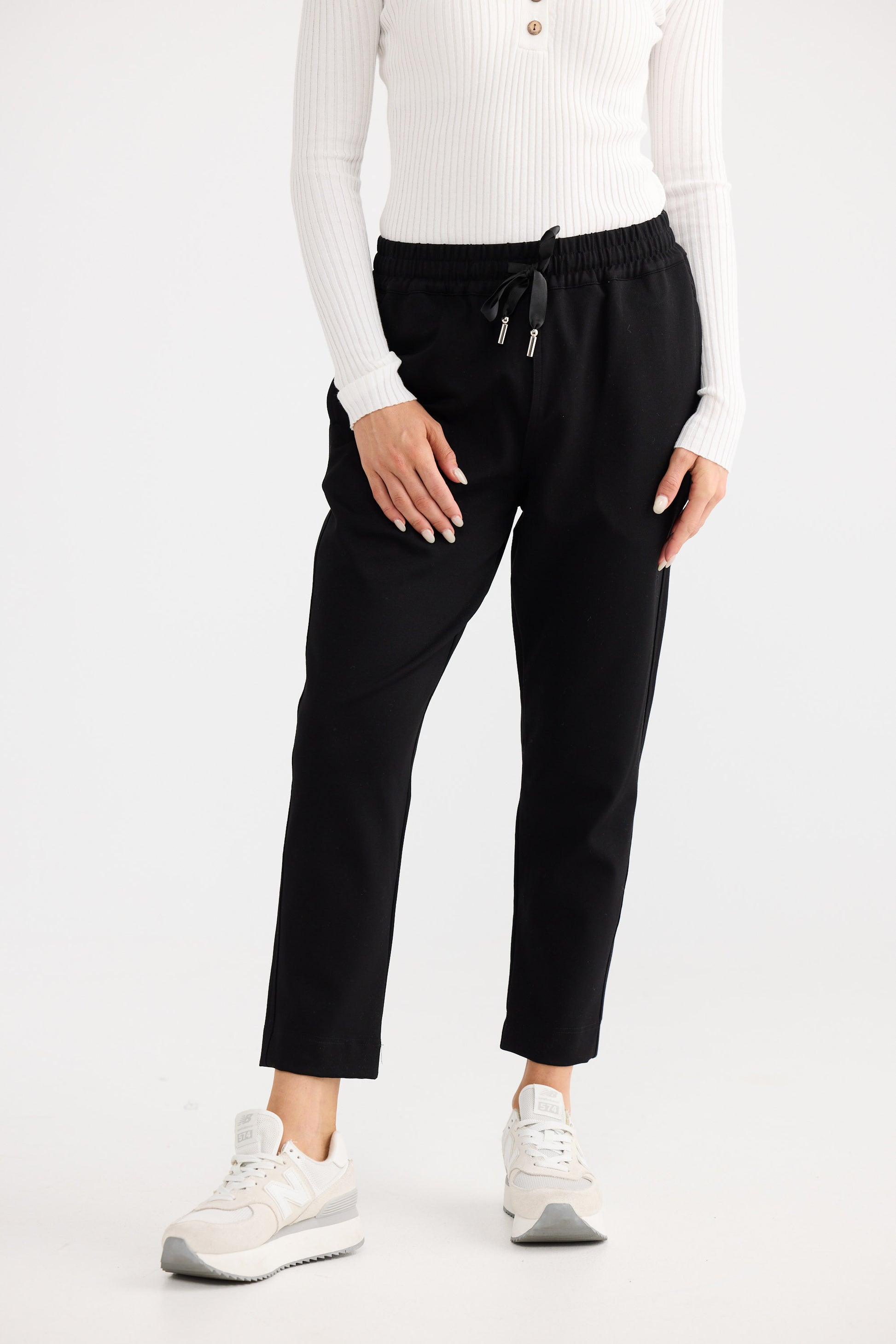 Person wearing black pants and a white top on a white background