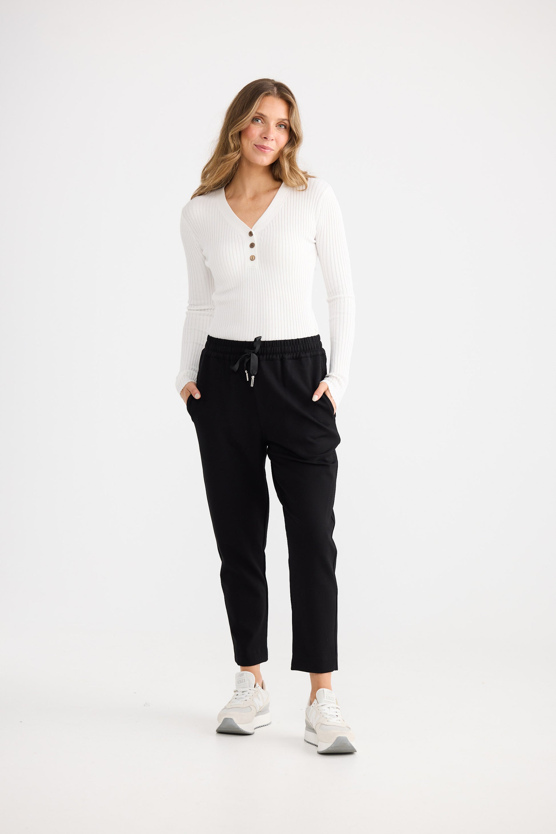 Person wearing black pants and a white top on a white background