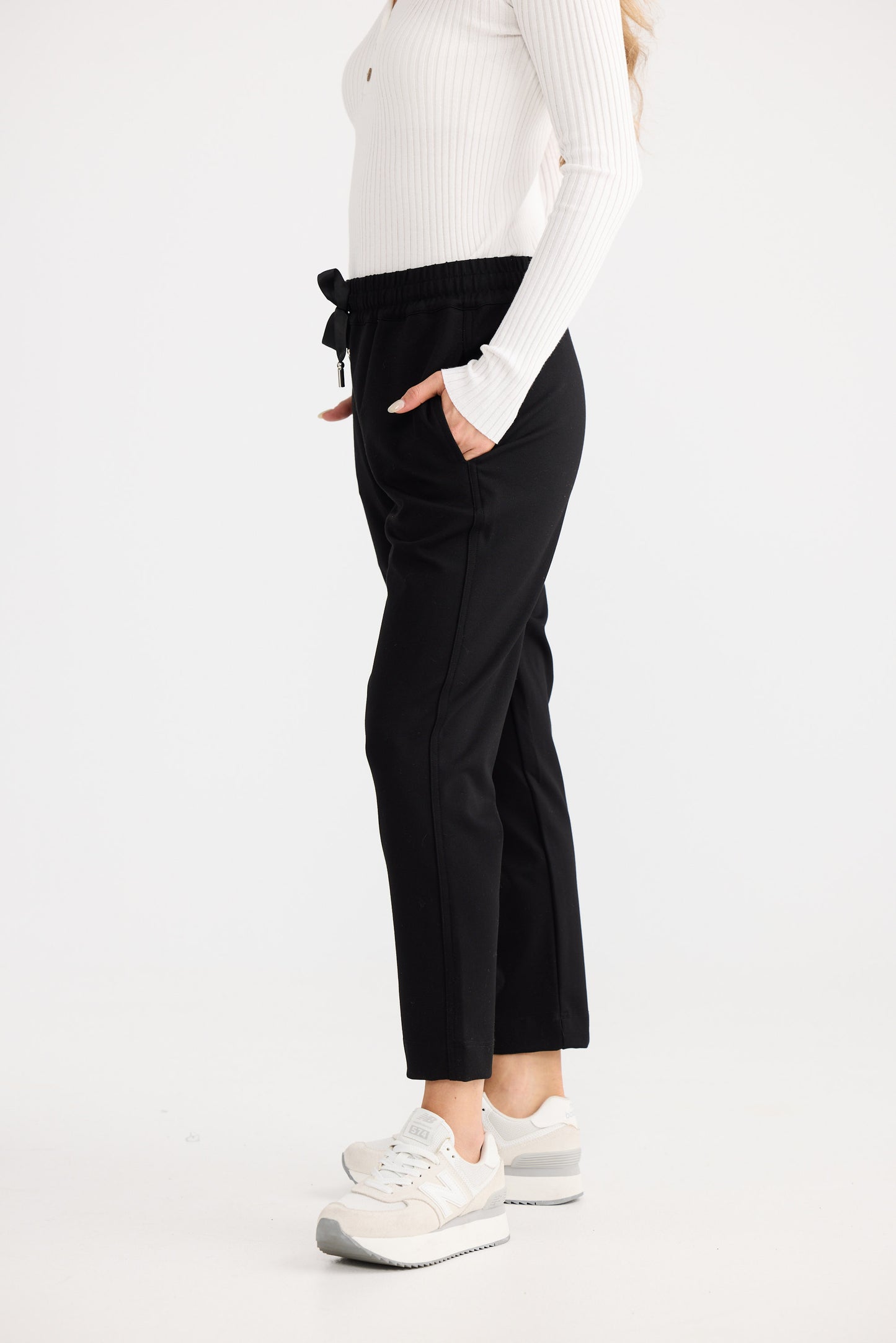 Person wearing black pants and a white top on a white background