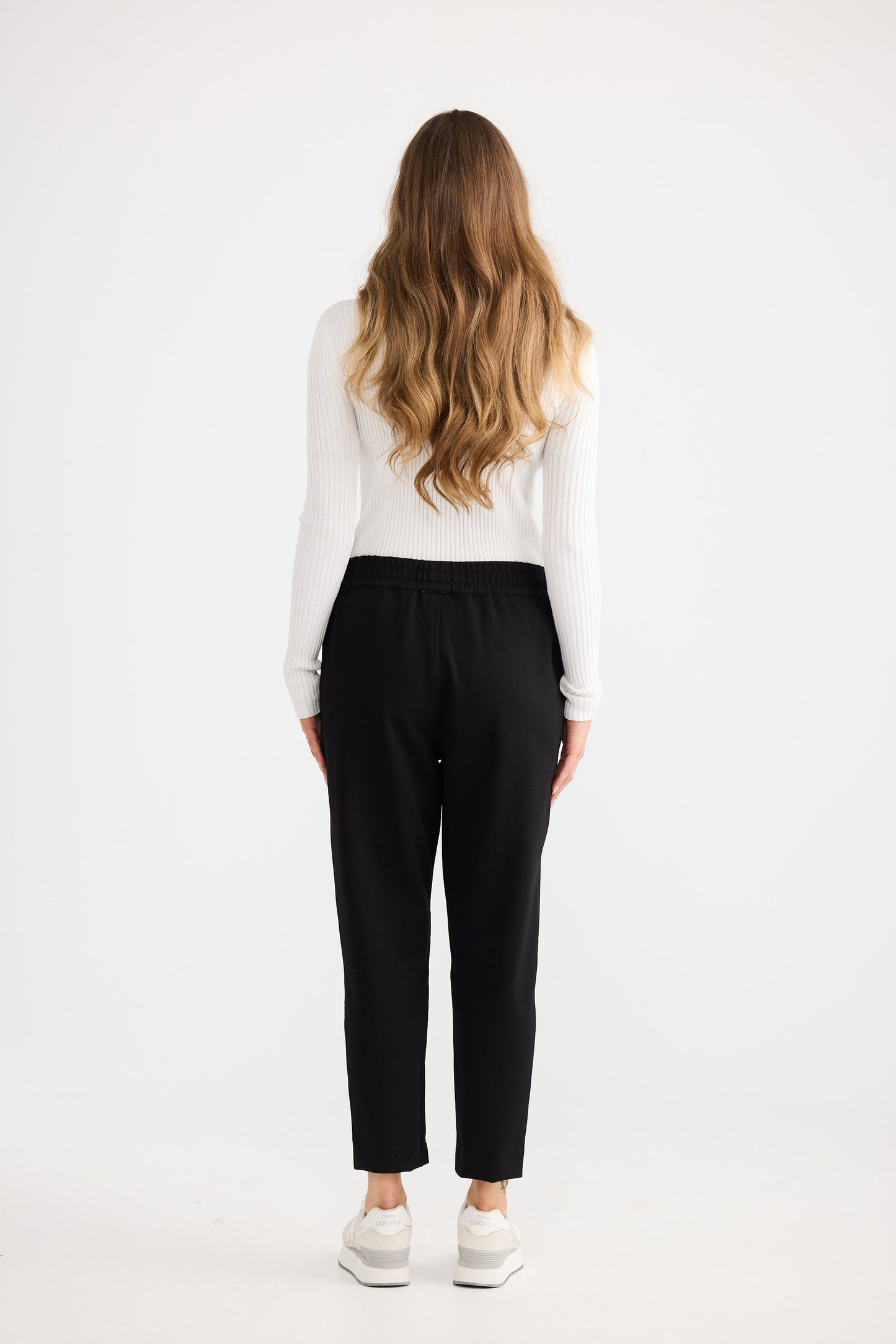 Person wearing a white top and black pants on a white background
