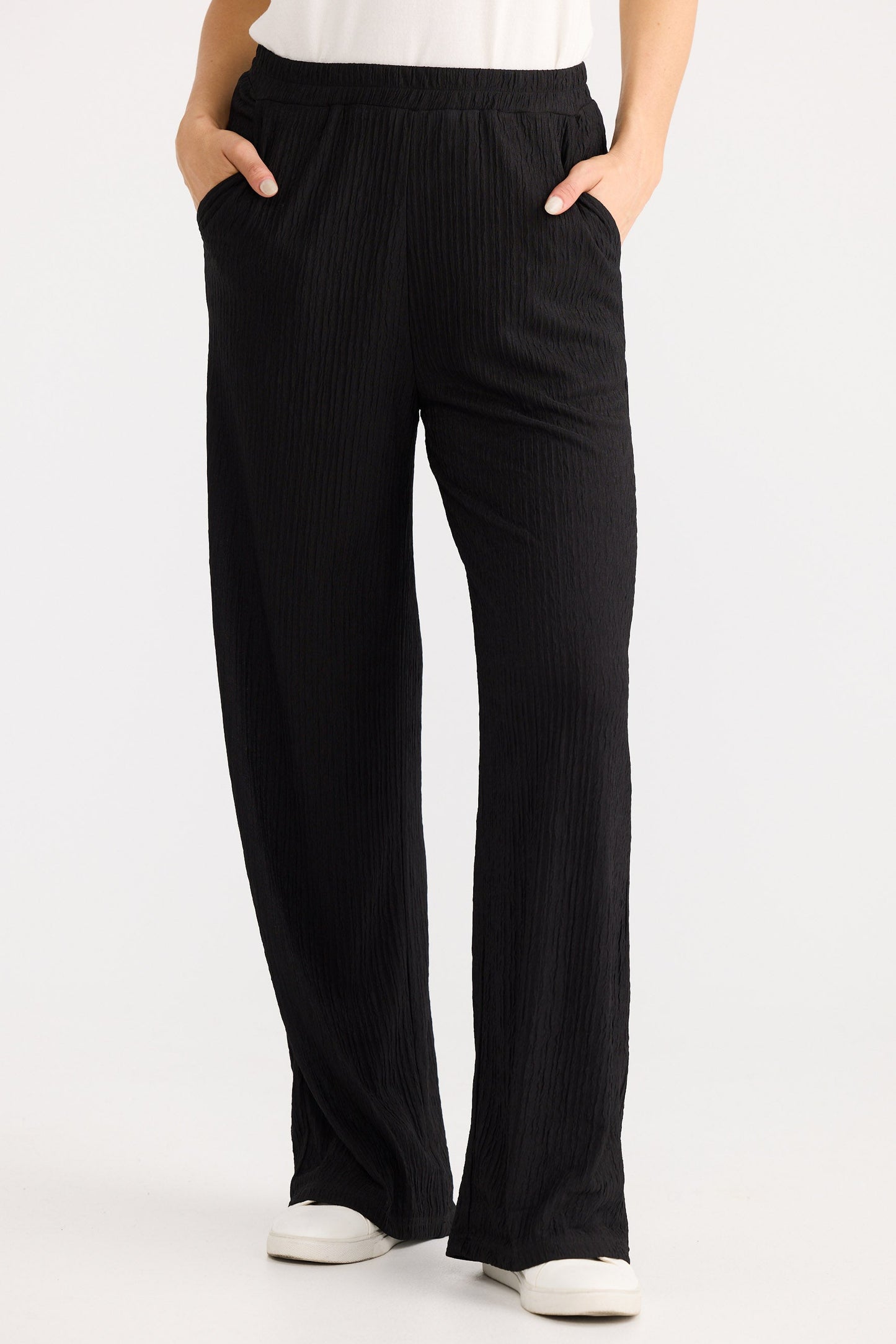 Person wearing black wide-leg pants on a white background