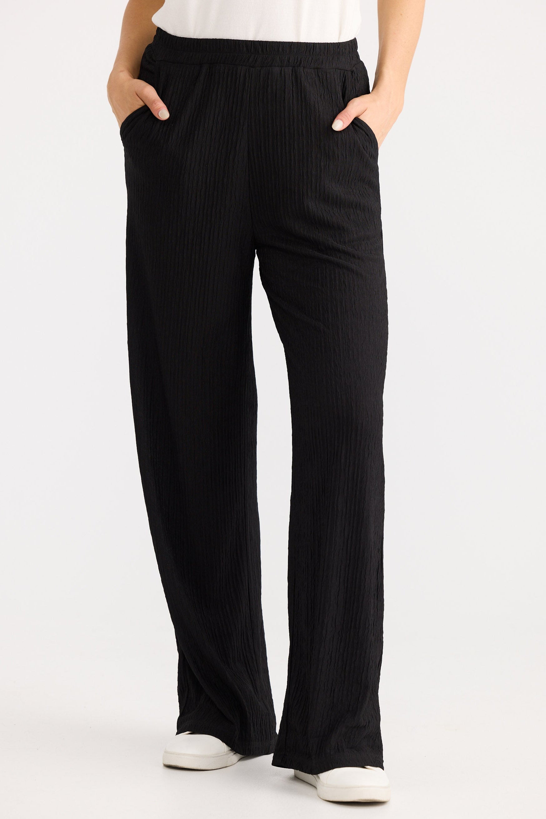 Person wearing black wide-leg pants on a white background
