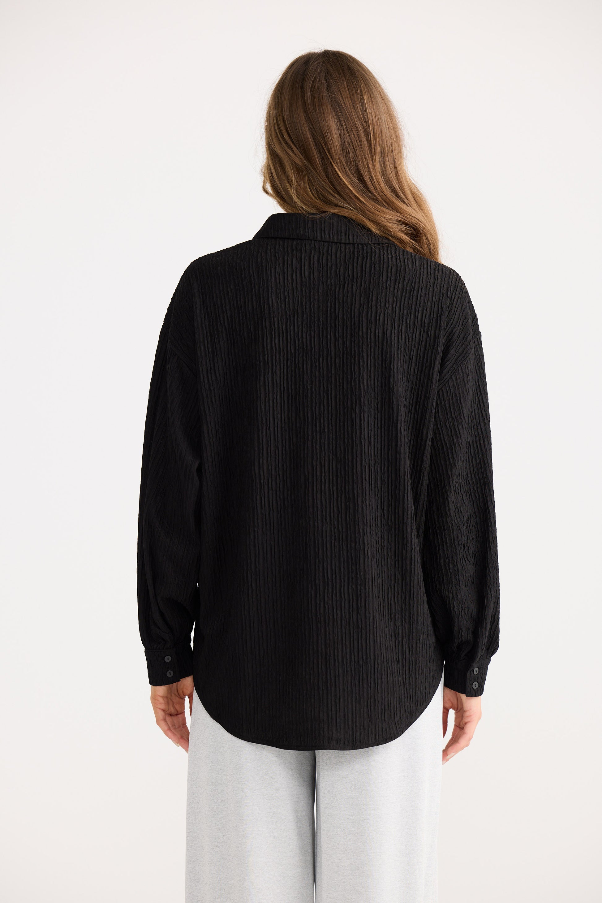 Person wearing a black ribbed sweater on a white background