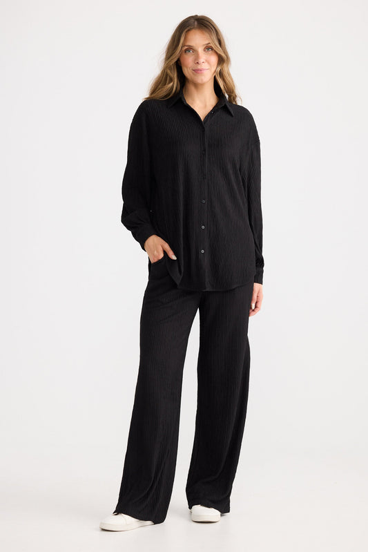 Woman wearing a black shirt and pants set on a white background