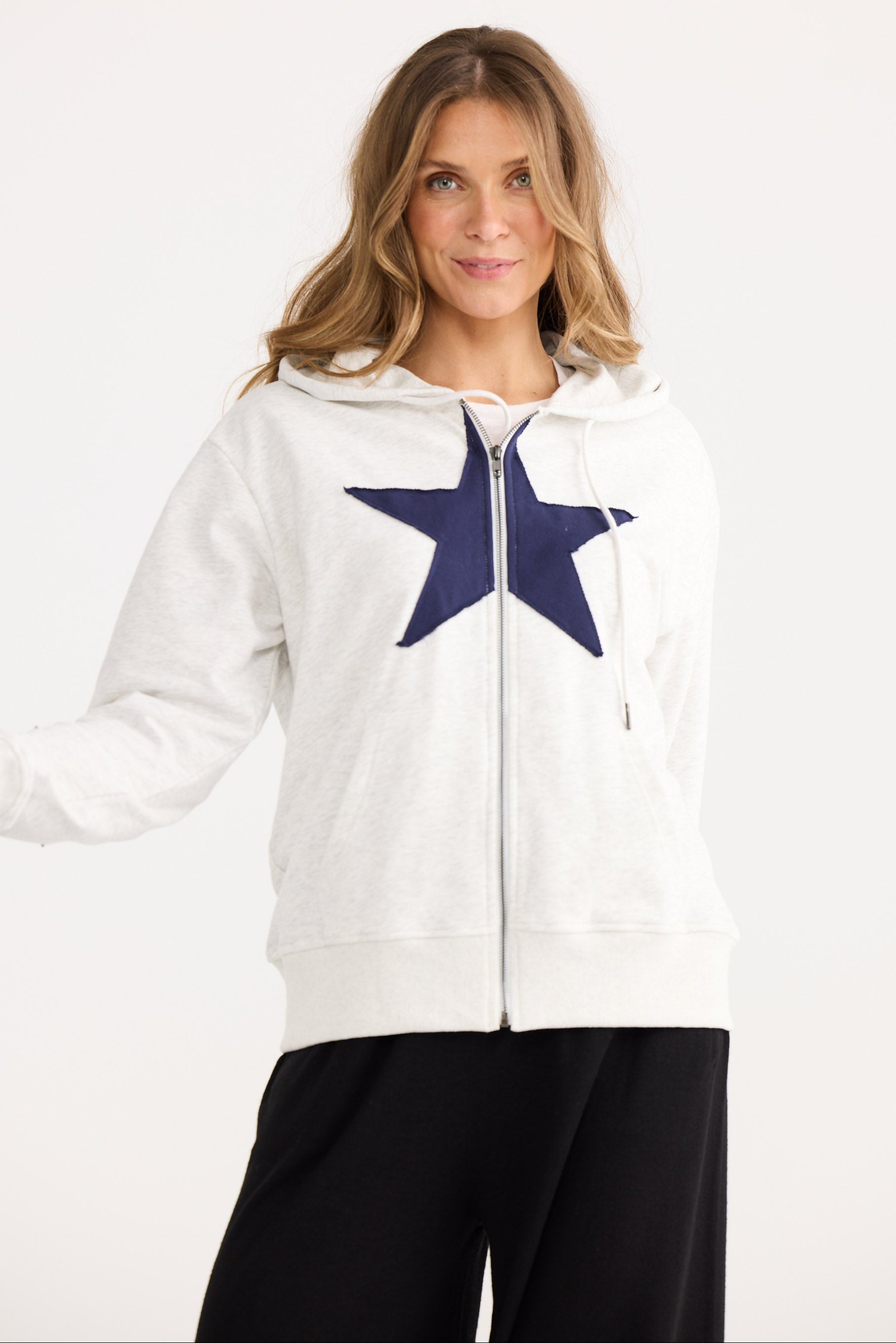 Woman wearing a white hoodie with a blue star design on a white background