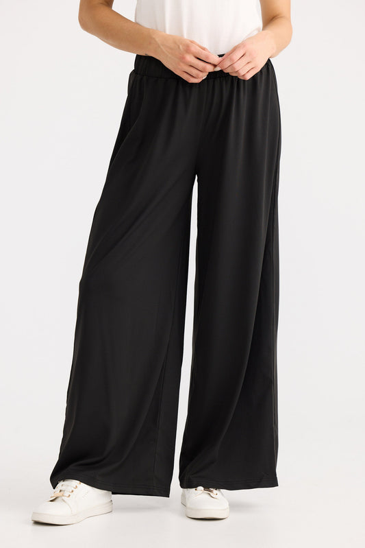 Person wearing black wide-leg pants on a white background