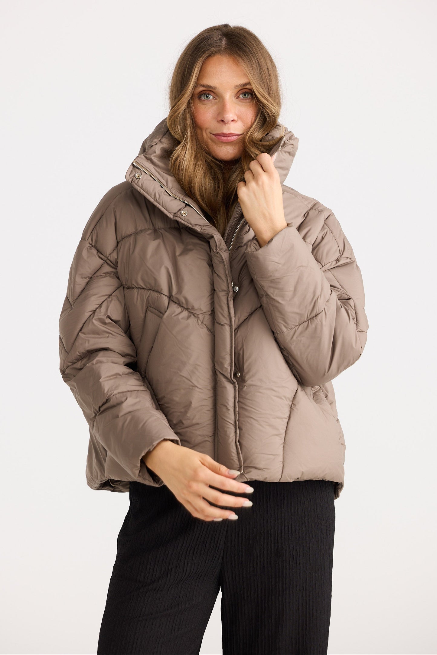 Woman wearing a beige puffer jacket on a white background