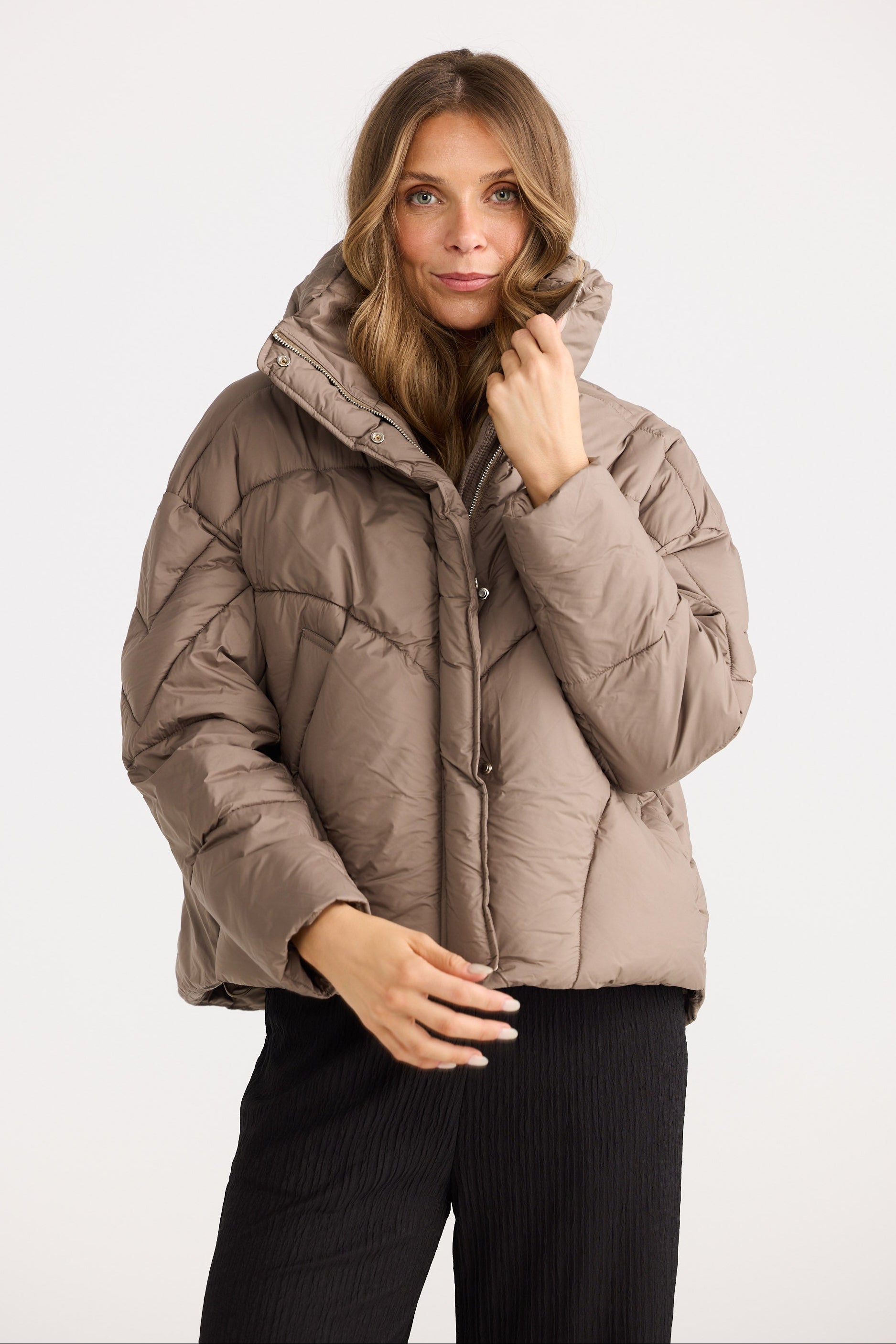 Woman wearing a beige puffer jacket on a white background