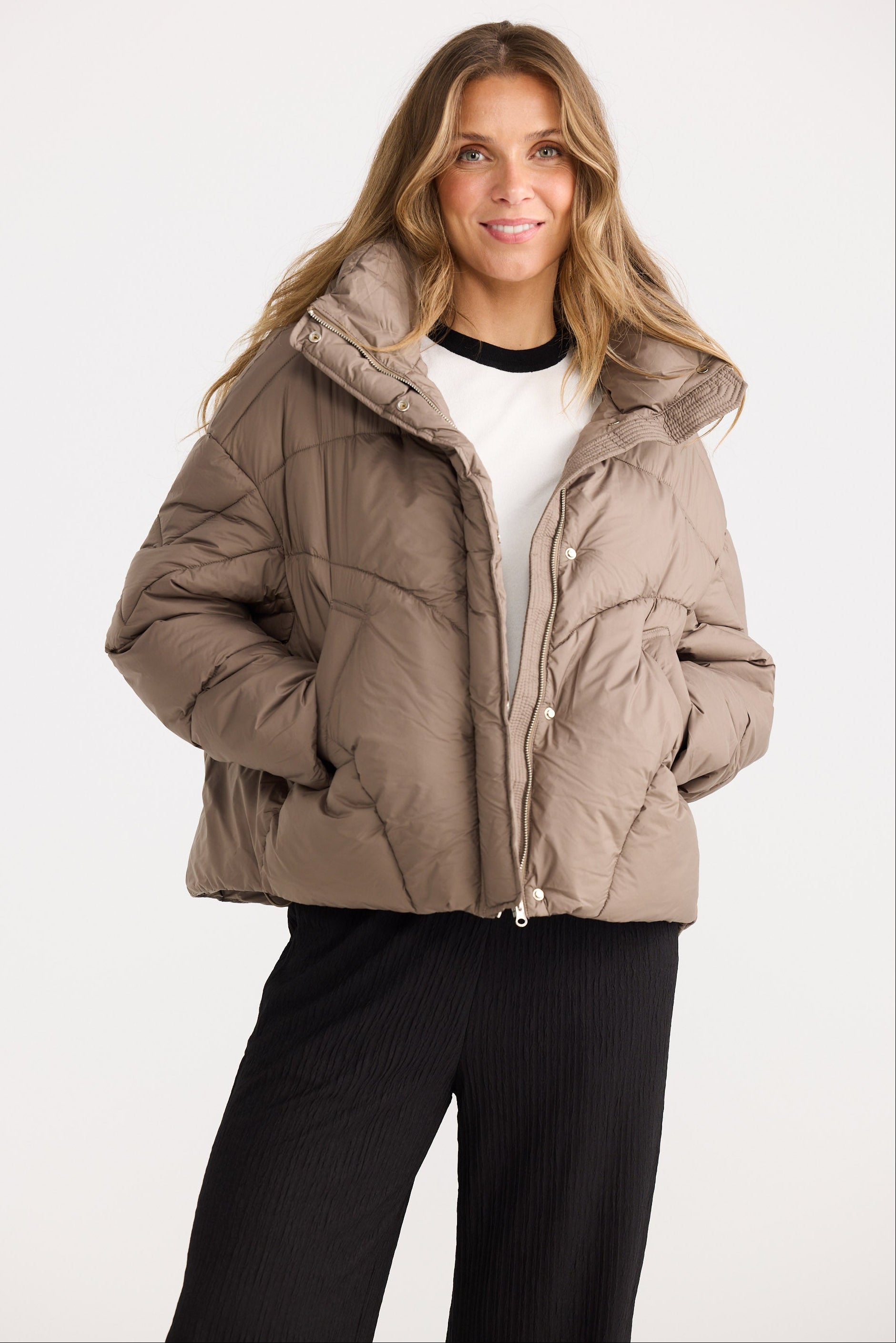Woman wearing a beige puffer jacket on a white background