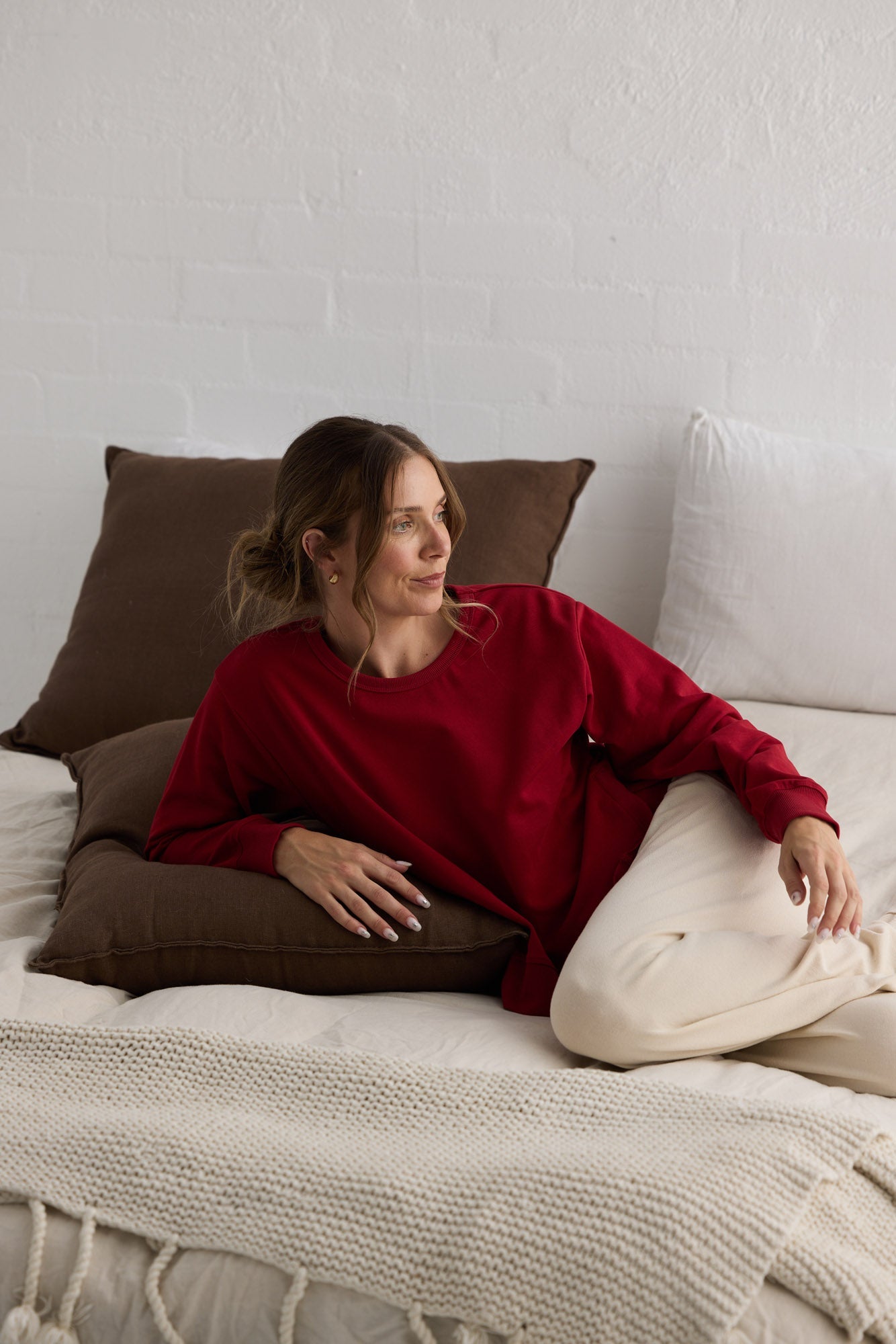 Campaign image of model wearing Faye Lounge Jumper in scarlet.