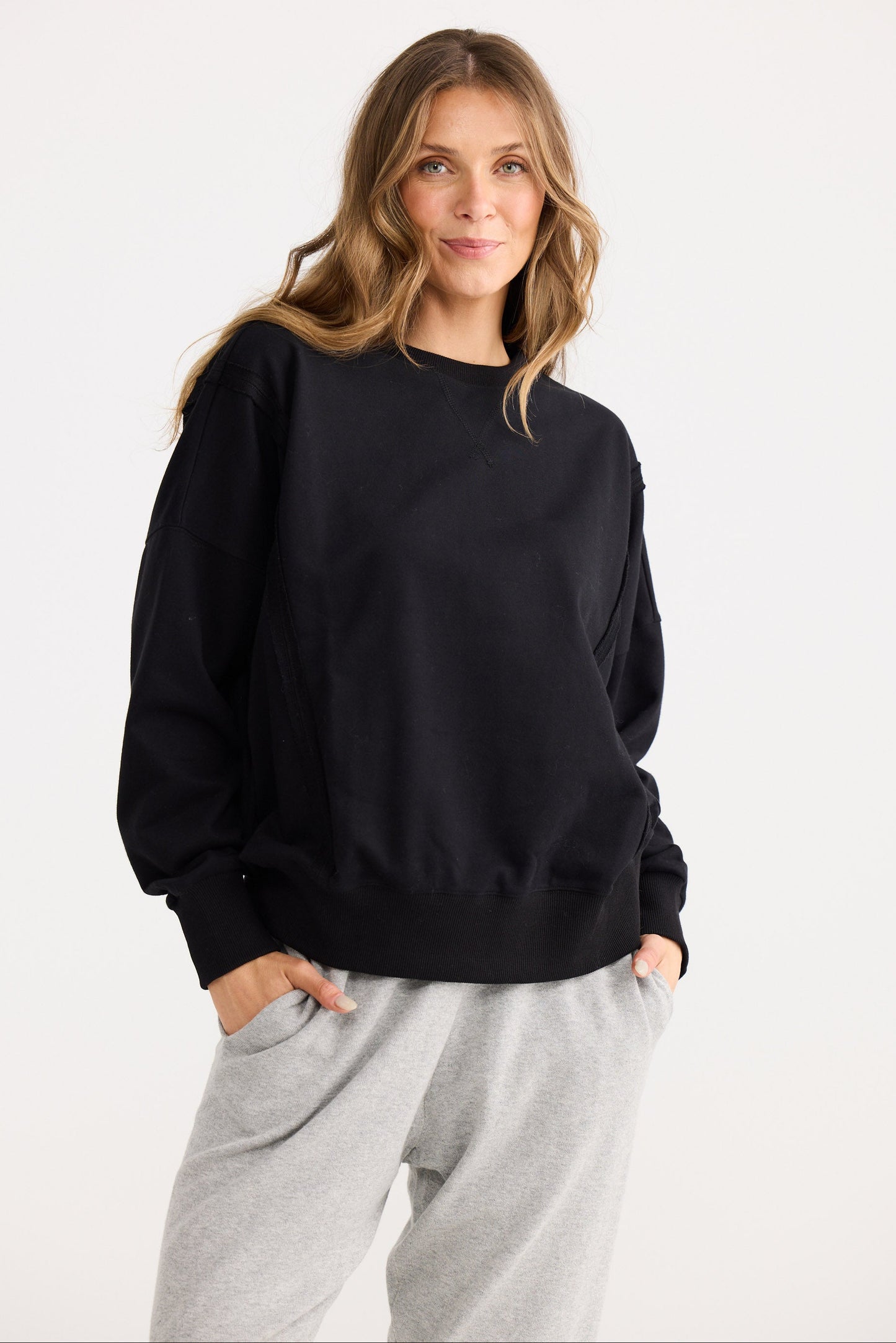 Woman wearing a black sweatshirt and gray pants on a white background
