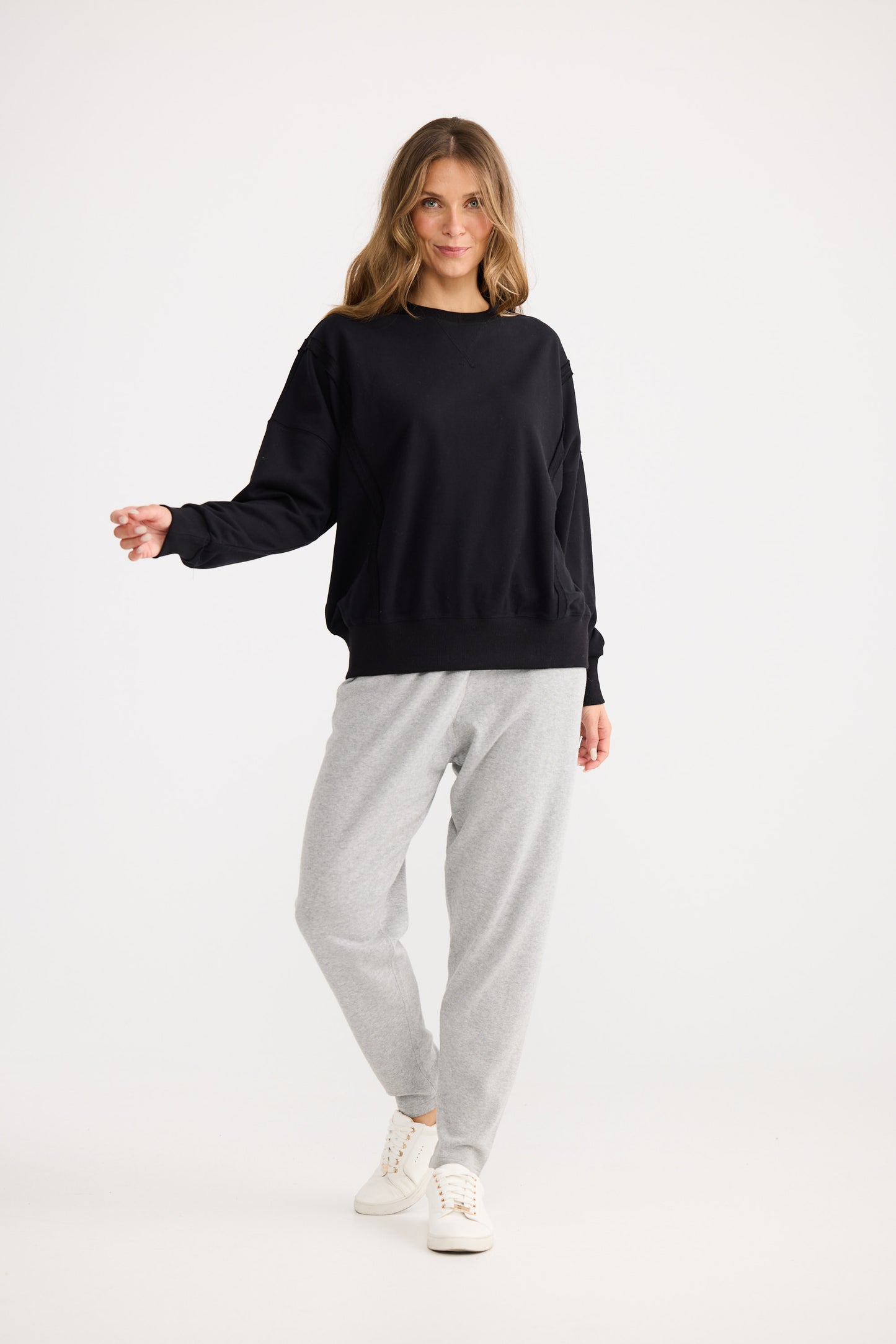 Woman wearing a black sweater and gray pants on a white background