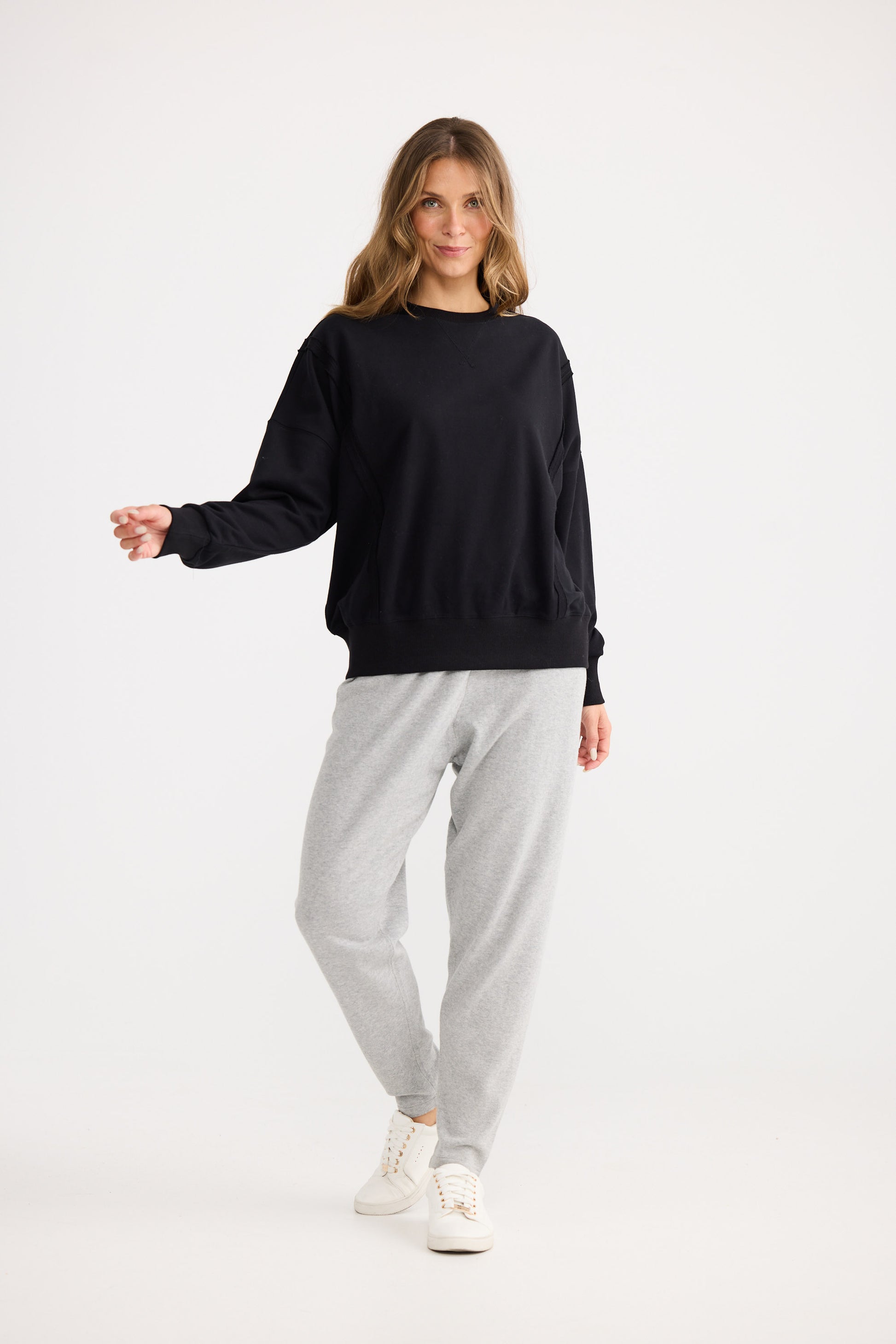 Woman wearing a black sweater and gray pants on a white background