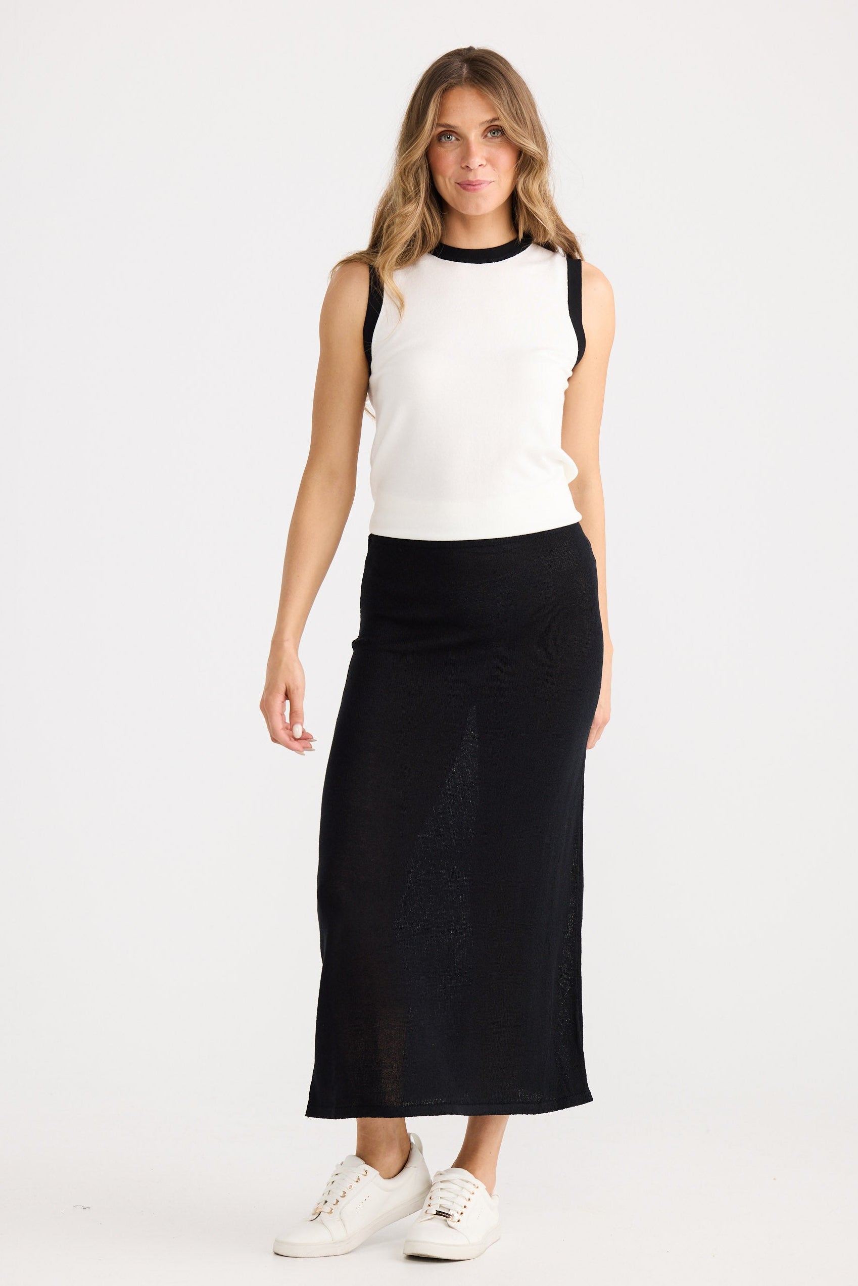 Woman wearing a white top and black skirt on a white background