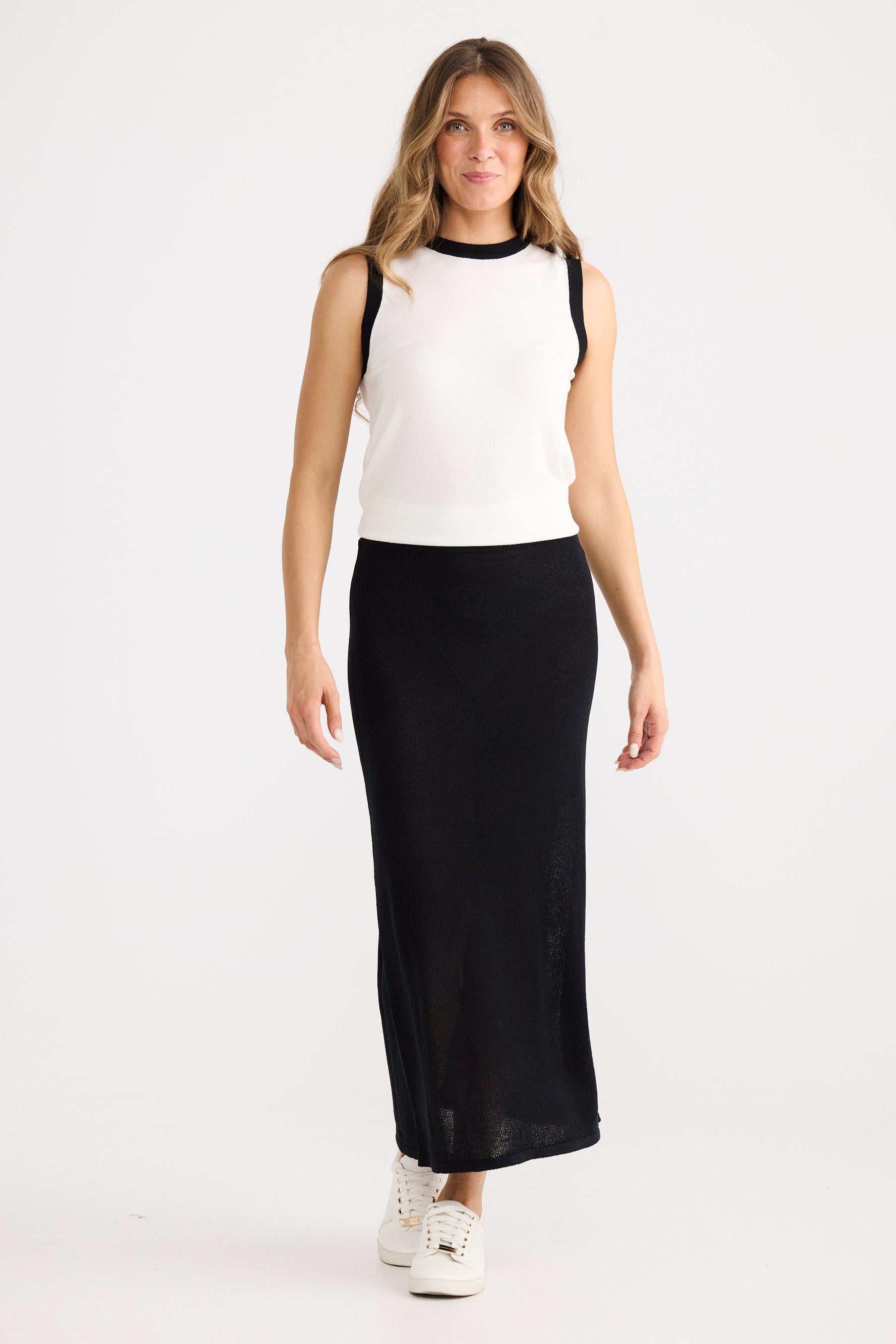 Woman wearing a white top and black skirt on a white background