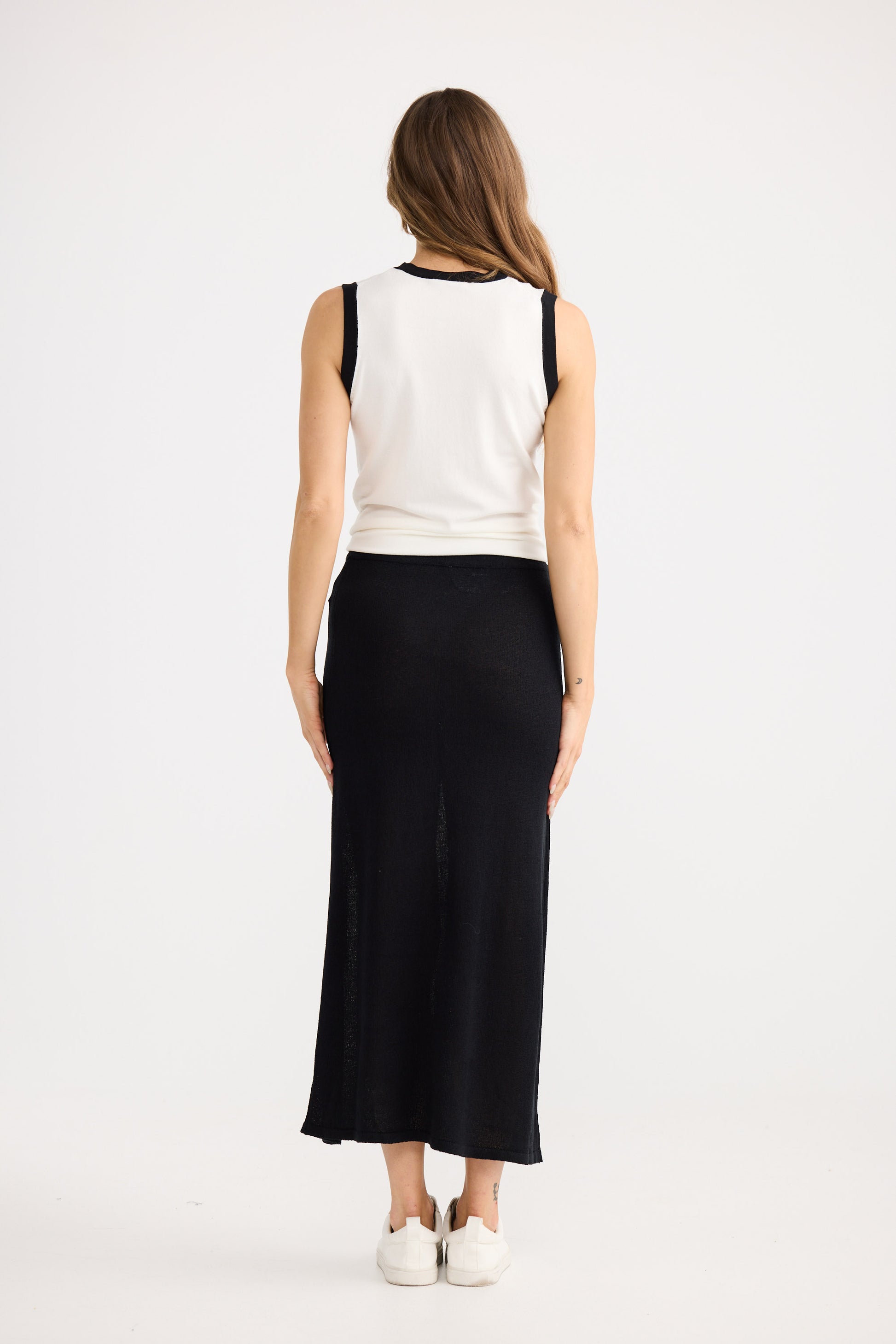 Woman wearing a white sleeveless top and black skirt on a white background