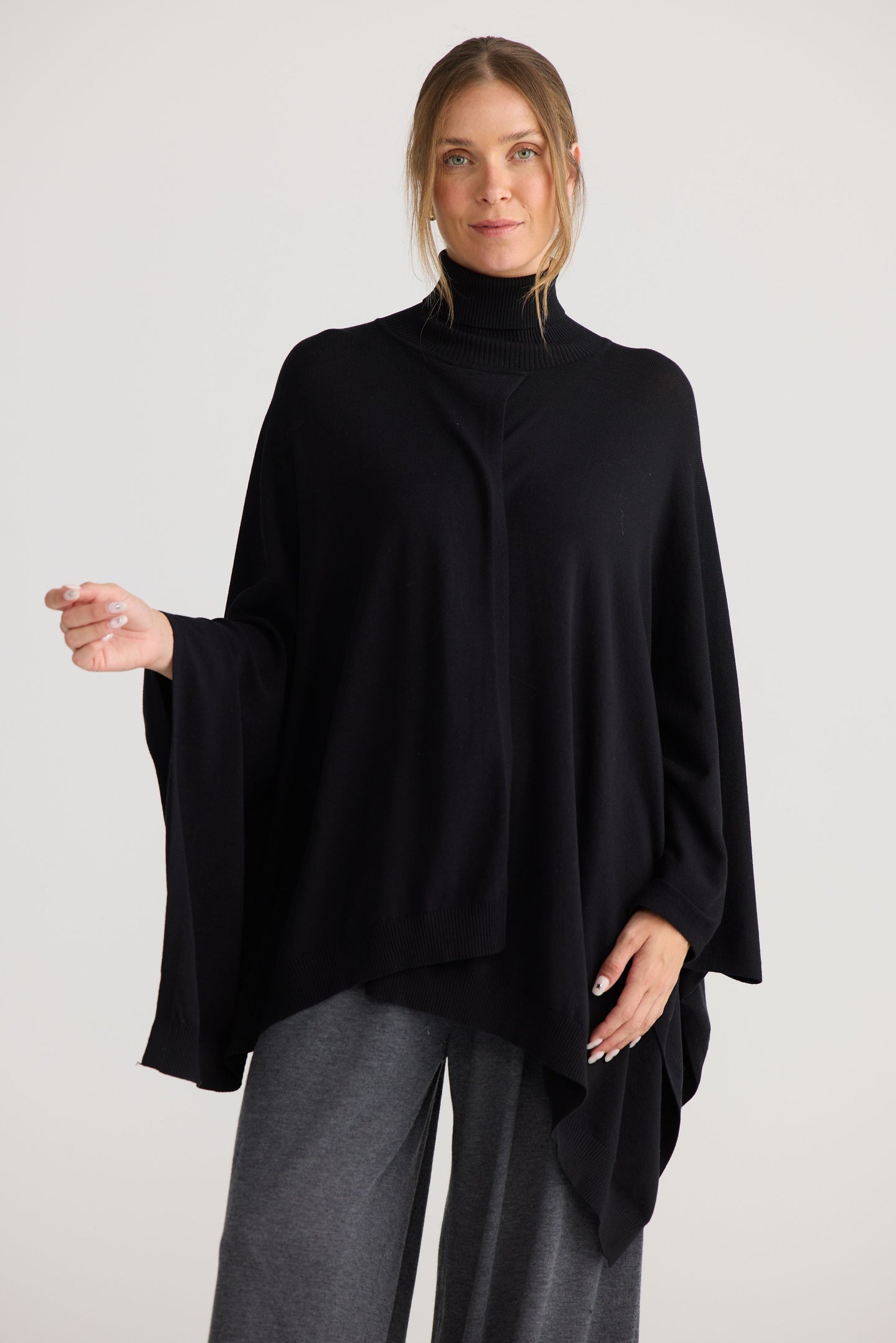 Model wearing Awaken Knit Cape in black, styled for everyday wear.