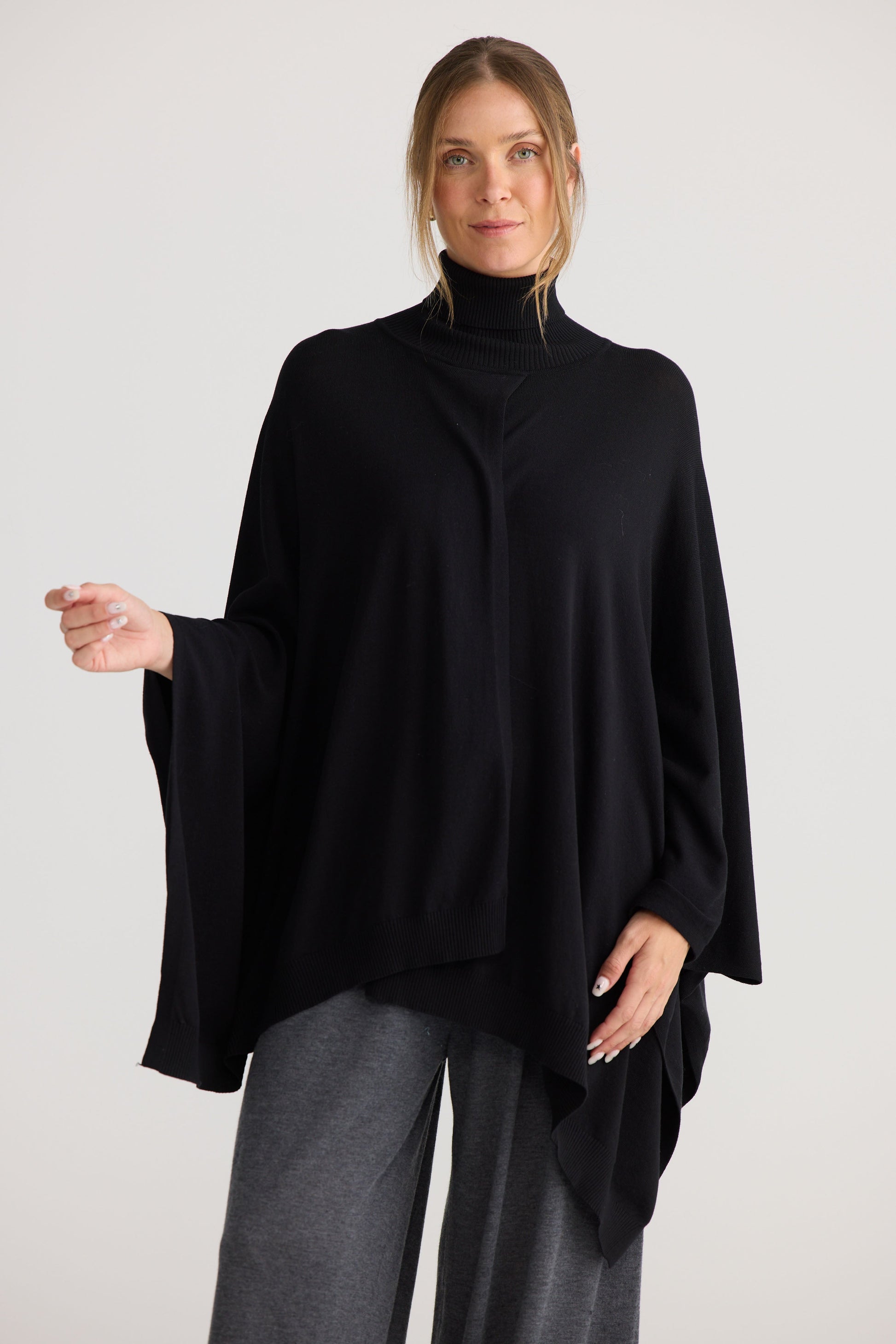 Model wearing Awaken Knit Cape in black, styled for everyday wear.