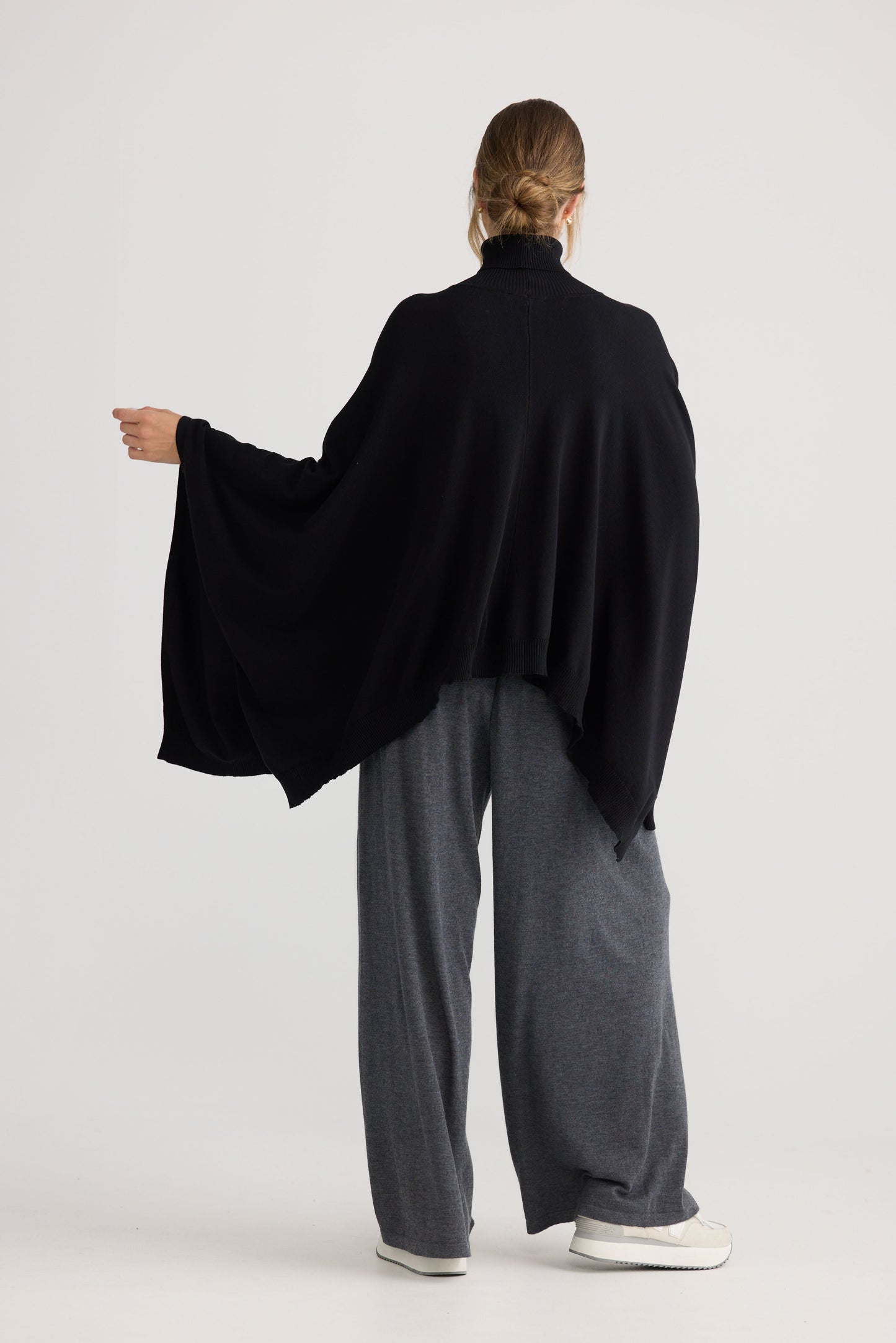 Model wearing Awaken Knit Cape in black, studio product image.